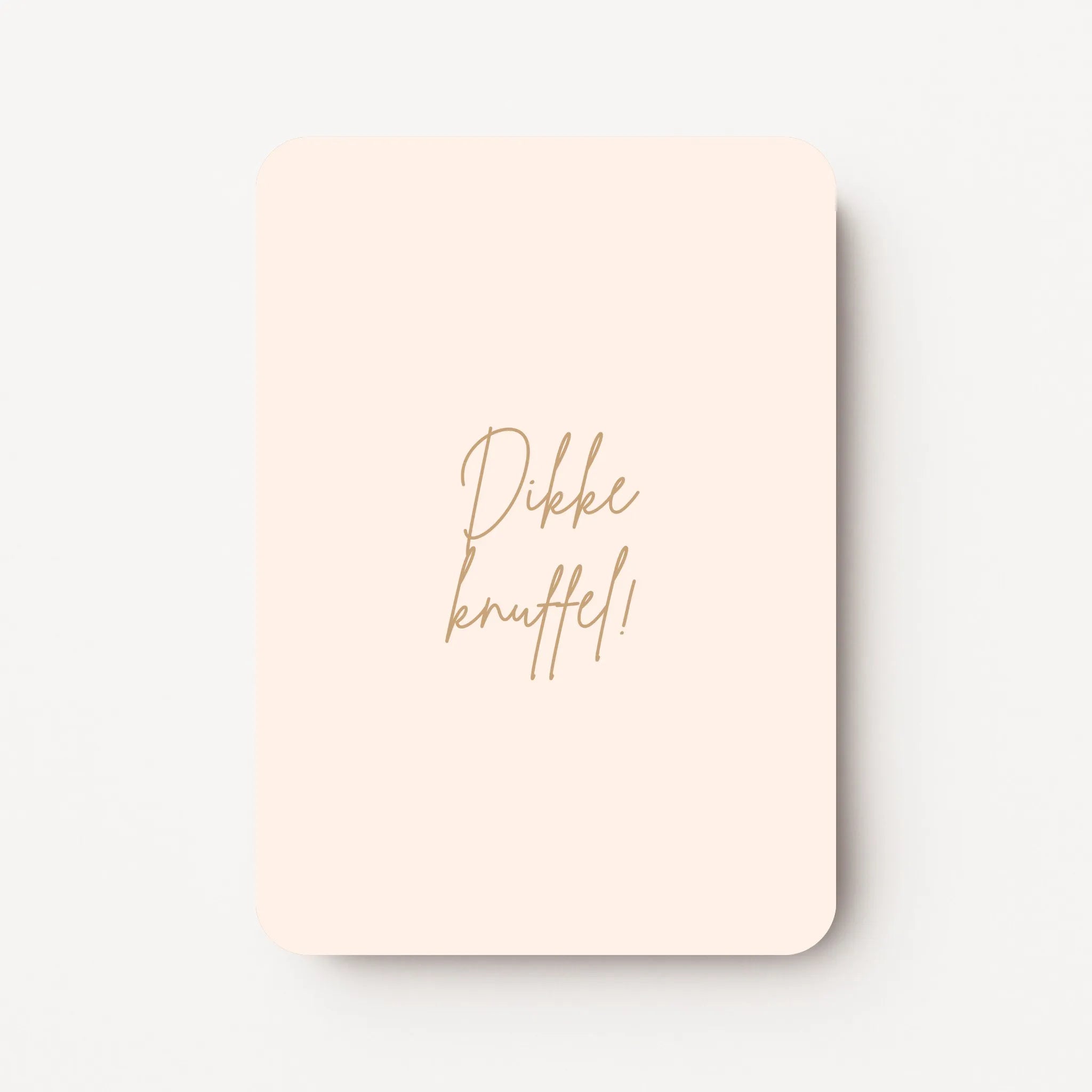 Staande beterschapskaart met beige-roze achtergrond en tekst in warme zandtint ‘Dikke knuffel!’, flatlay op witte ondergrond.