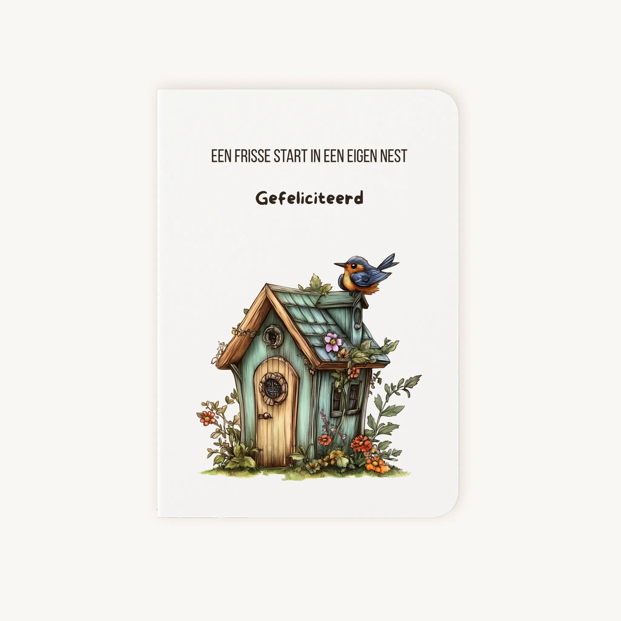 Staande dubbelgevouwen kaart nieuwe woning met afgeronde hoekjes en aquarelillustratie van een vogelhuisje met bloemen en een blauw vogeltje, met de tekst Een frisse start in een eigen nest Gefeliciteerd, flatlay op lichte achtergrond.
