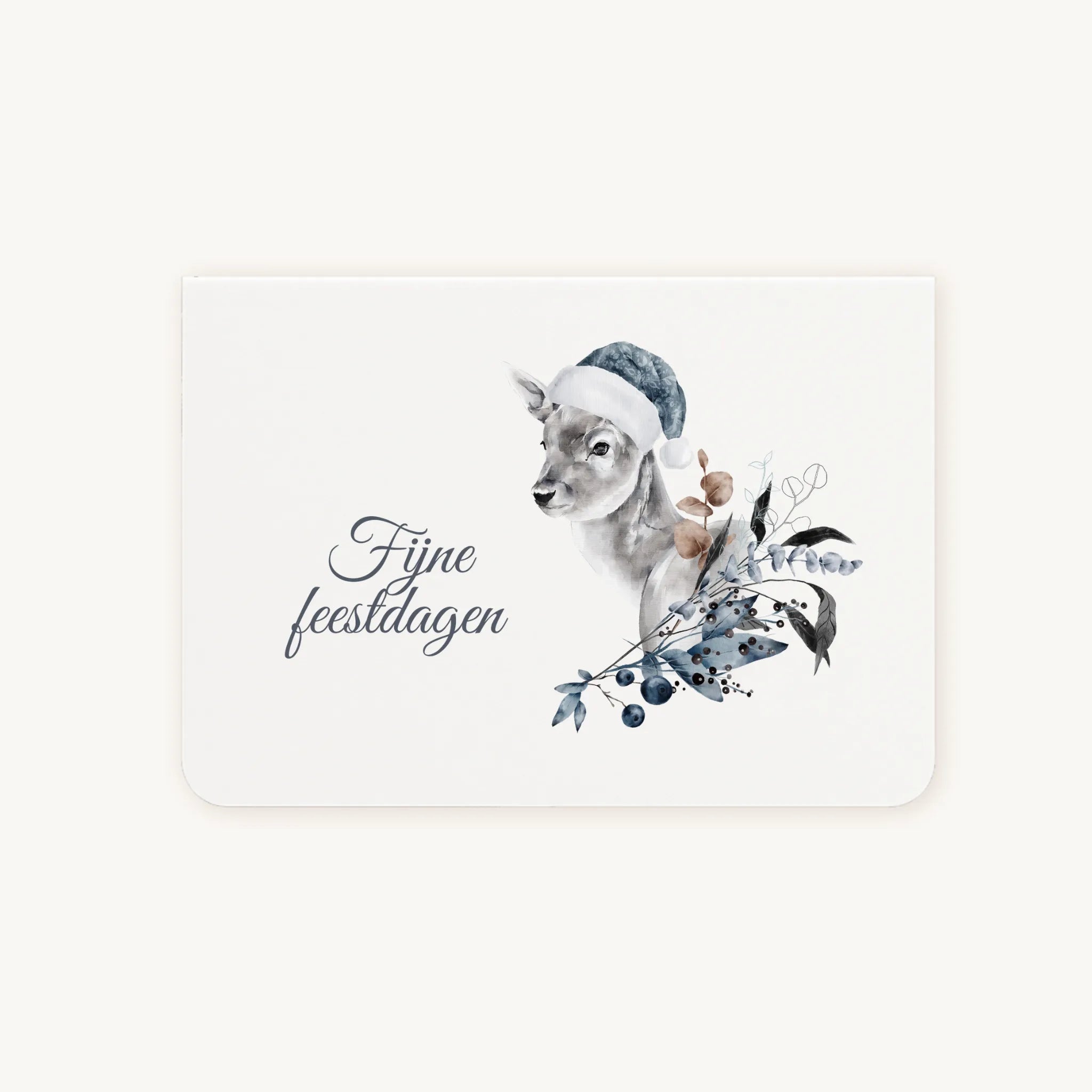 Liggende dubbelgevouwen kerstkaart met aquarelillustratie van een schattig hert met blauwe kerstmuts, omringd door winterse bladeren en bessen, sierlijke tekst ‘fijne feestdagen’, flatlay op lichte achtergrond.