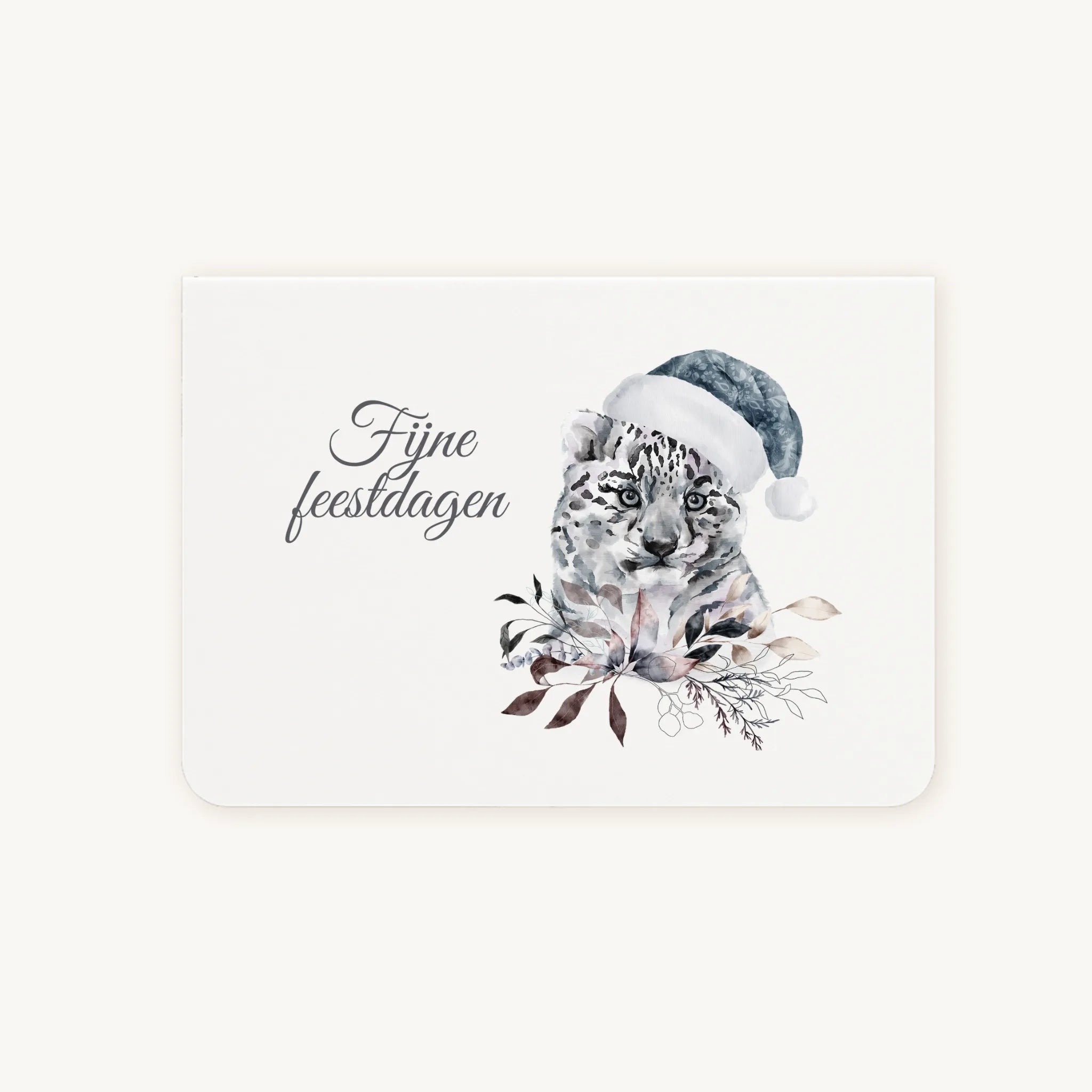 Liggende dubbelgevouwen kerstkaart met aquarel sneeuwluipaard met blauwe kerstmanmuts, omringd door elegante wintertakjes en bladeren, sierlijke tekst ‘fijne feestdagen’, flatlay op lichte achtergrond.