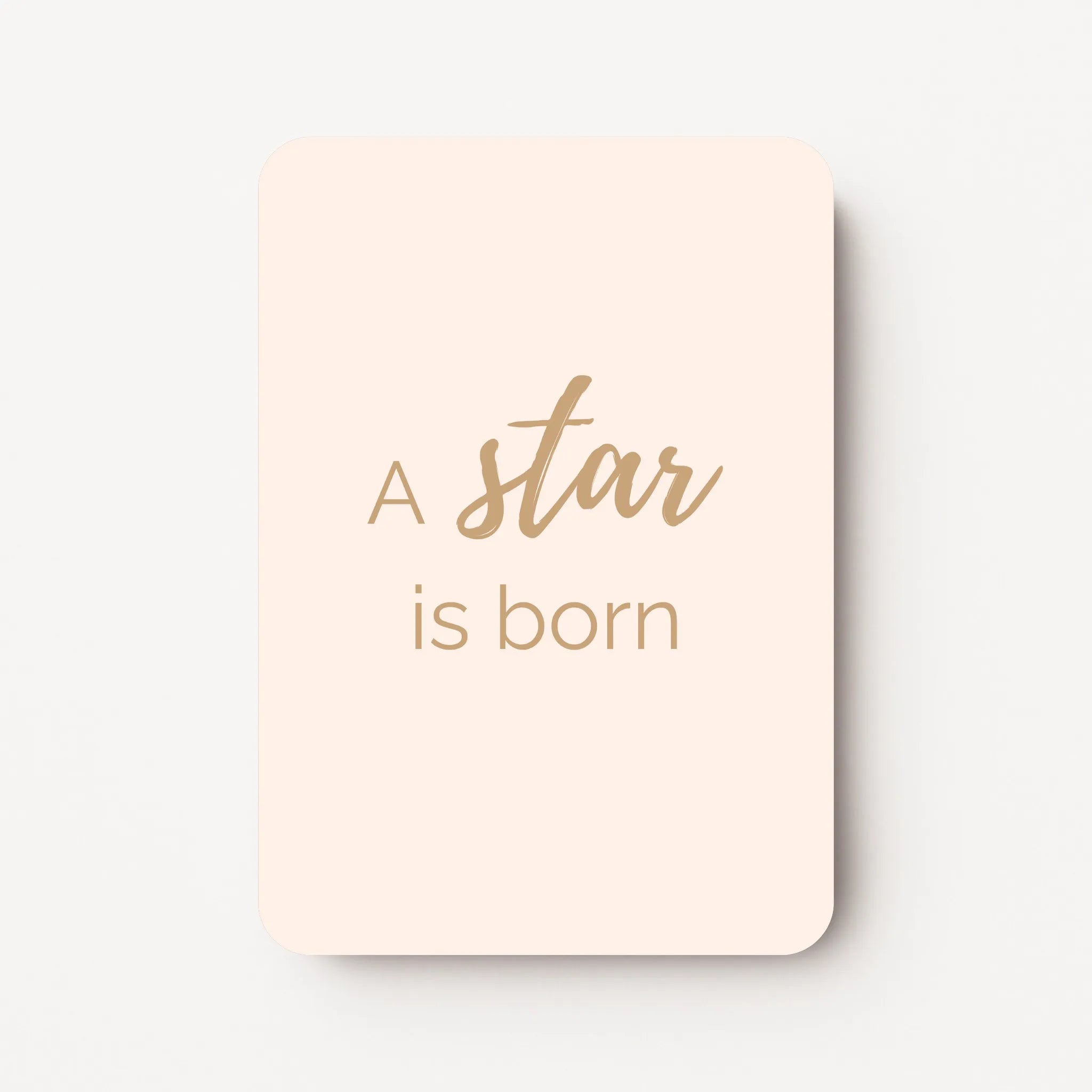 Staand minikaartje met tekst ‘A star is born’ in goudbeige letters, minimalistisch ontwerp op zachte perzik-witte achtergrond, flatlay op witte ondergrond.