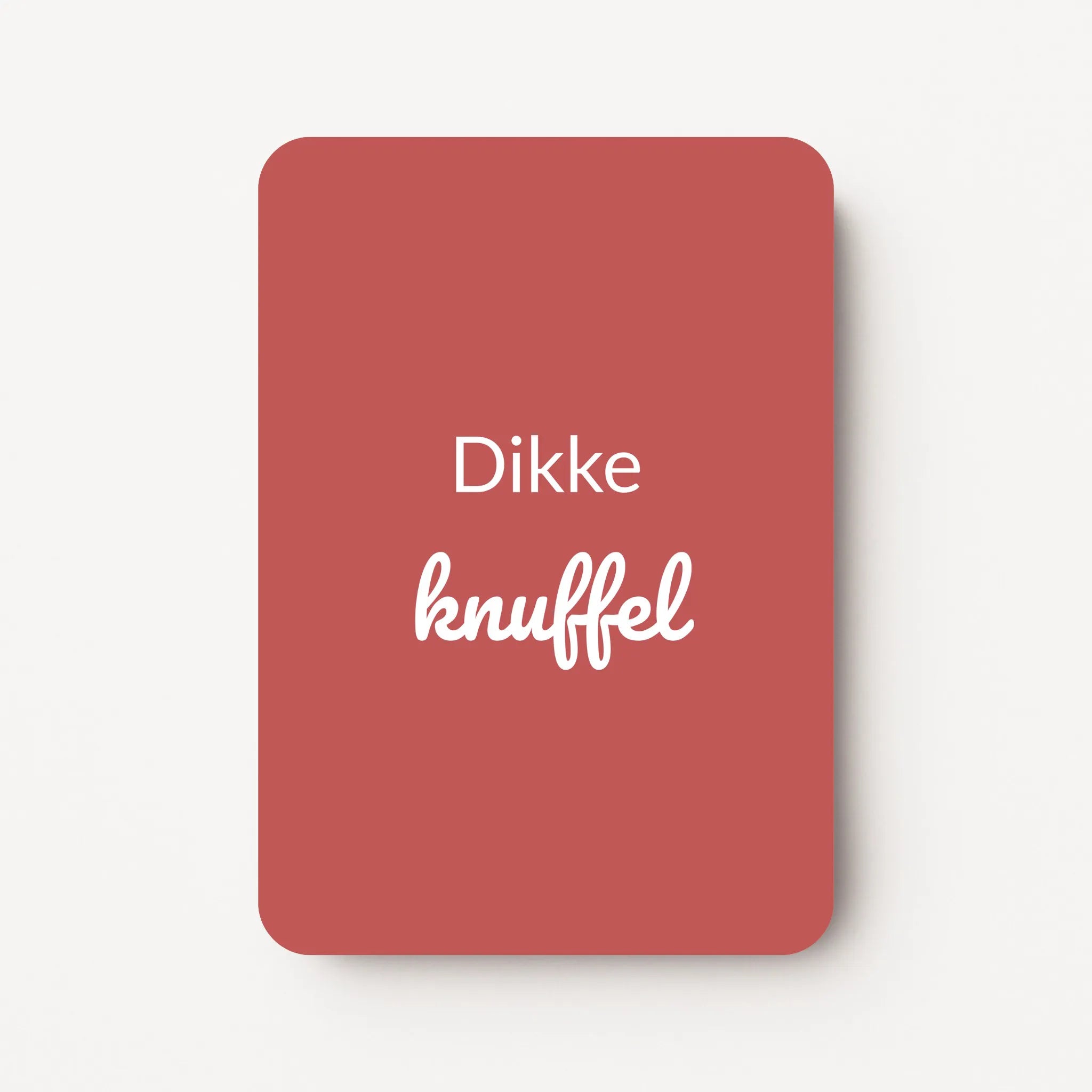 Staand minikaartje met witte tekst ‘Dikke knuffel’, minimalistisch ontwerp op een diepe bordeauxrode achtergrond, flatlay op witte ondergrond.