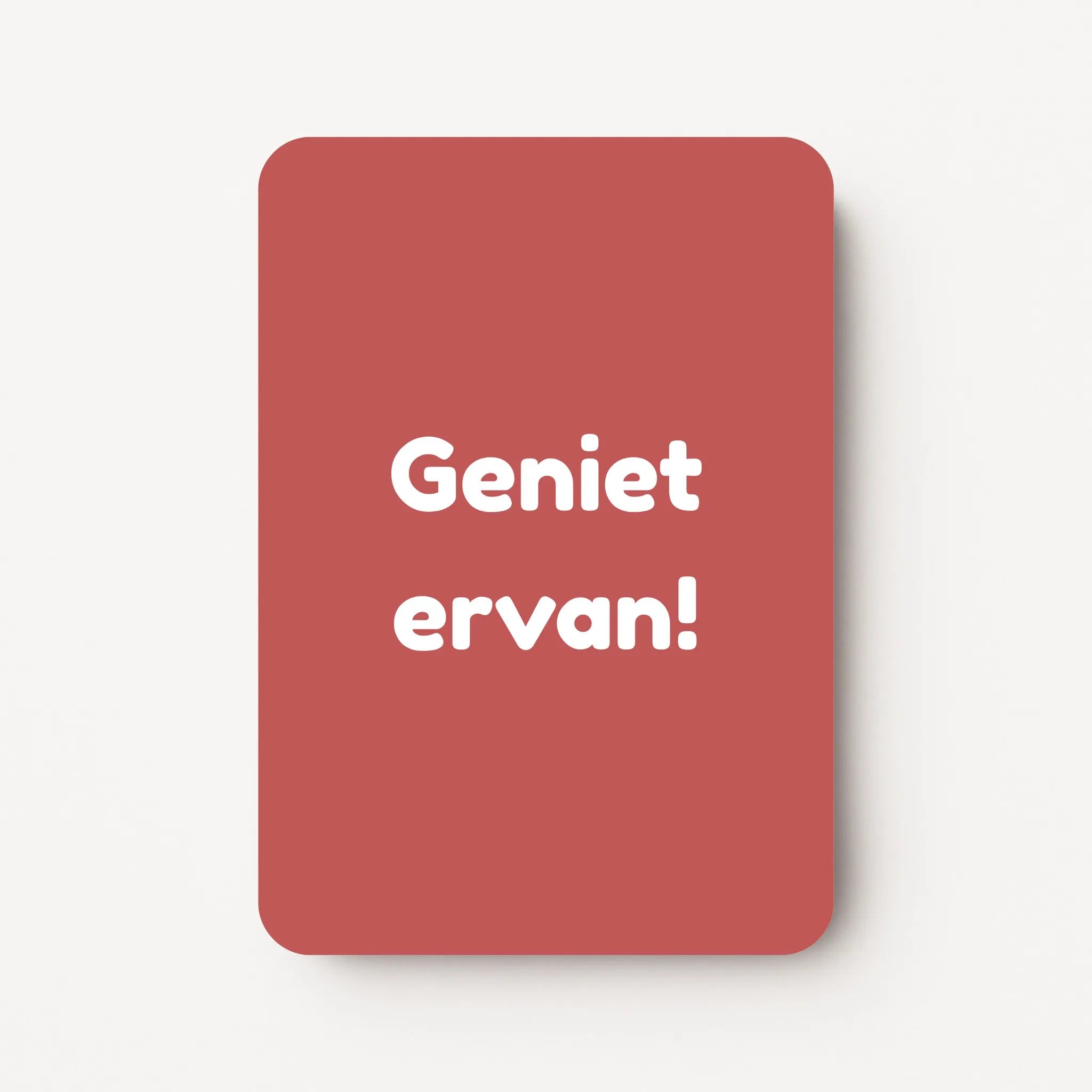 Staand minikaartje met tekst ‘Geniet ervan!’ in witte letters, minimalistisch ontwerp op warme roodroze achtergrond, flatlay op witte ondergrond.