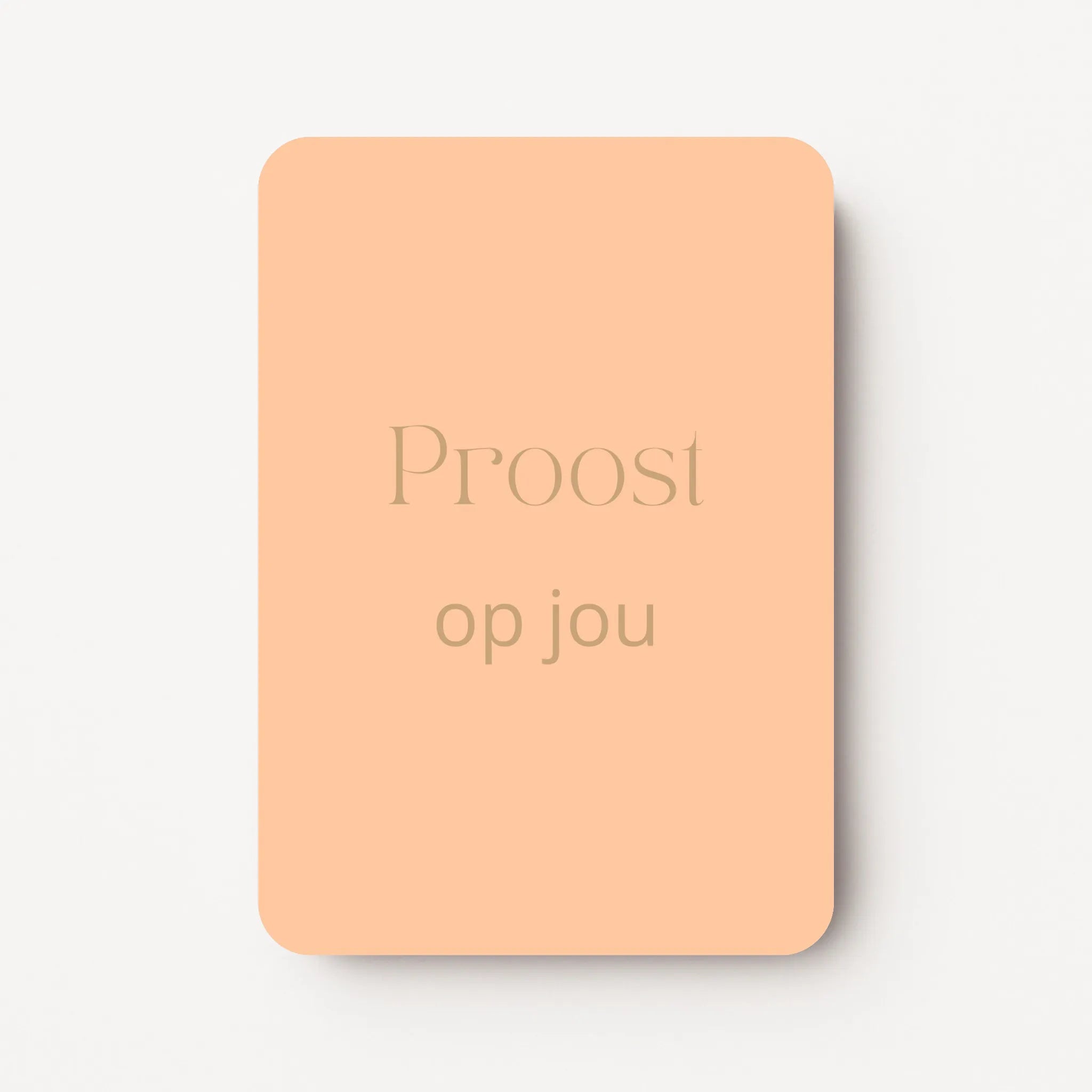 Staand minikaartje met goudbeige tekst ‘Proost op jou’, minimalistisch ontwerp op zachte perzikkleurige achtergrond, flatlay op witte ondergrond.