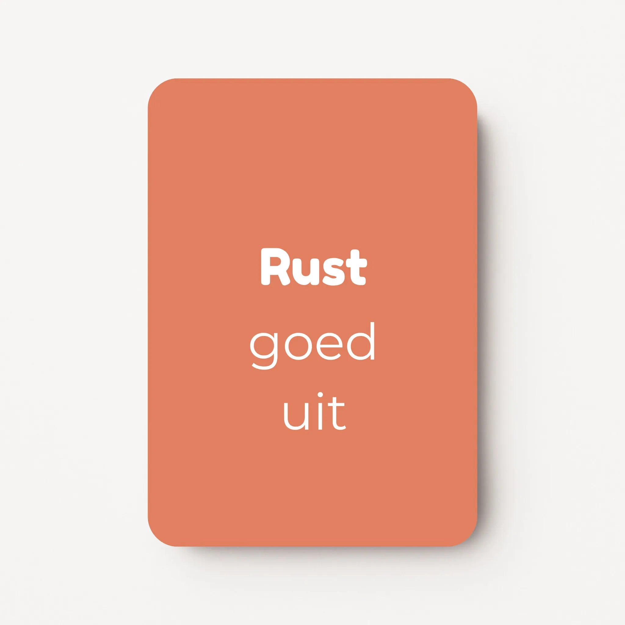 Staand minikaartje met tekst ‘Rust goed uit’ in witte letters, minimalistisch ontwerp op warme koraalroze achtergrond, flatlay op witte ondergrond.
