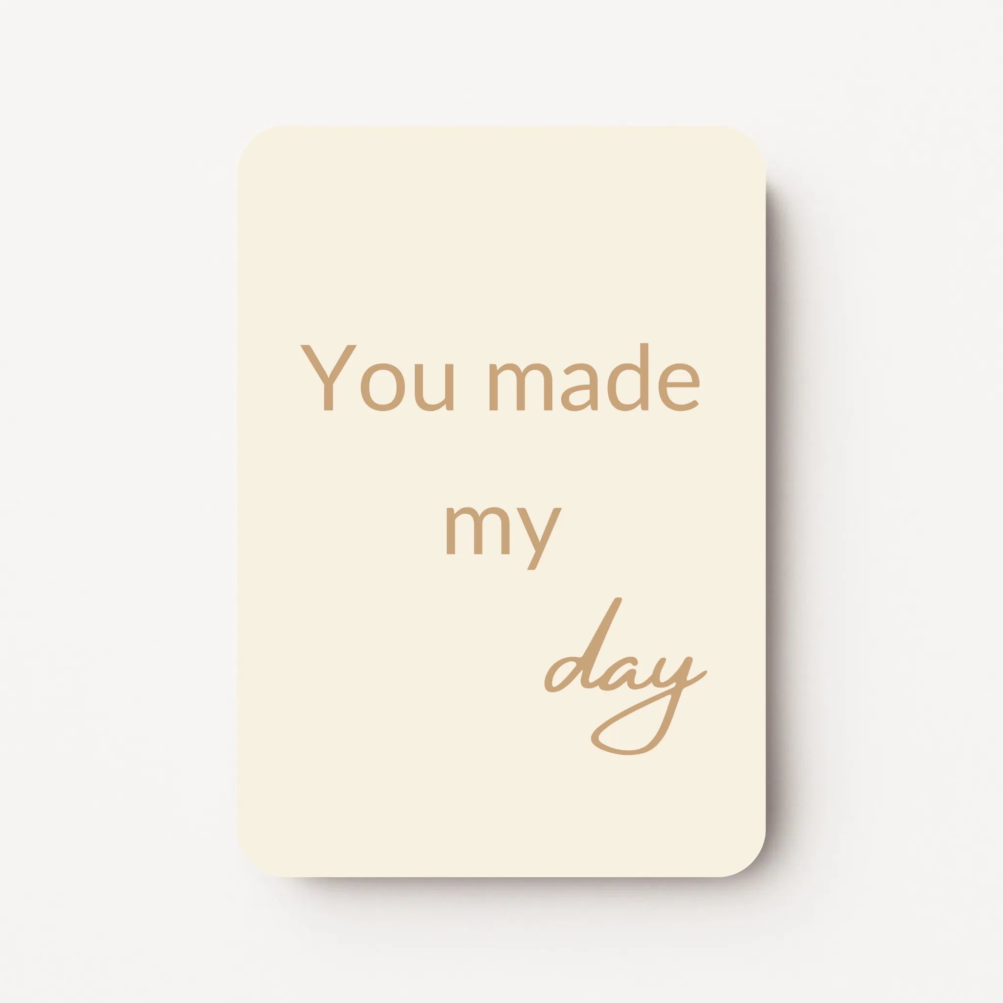 Staand minikaartje met tekst ‘You made my day’ in goudbeige letters, minimalistisch ontwerp op zachte crème achtergrond, flatlay op witte ondergrond.