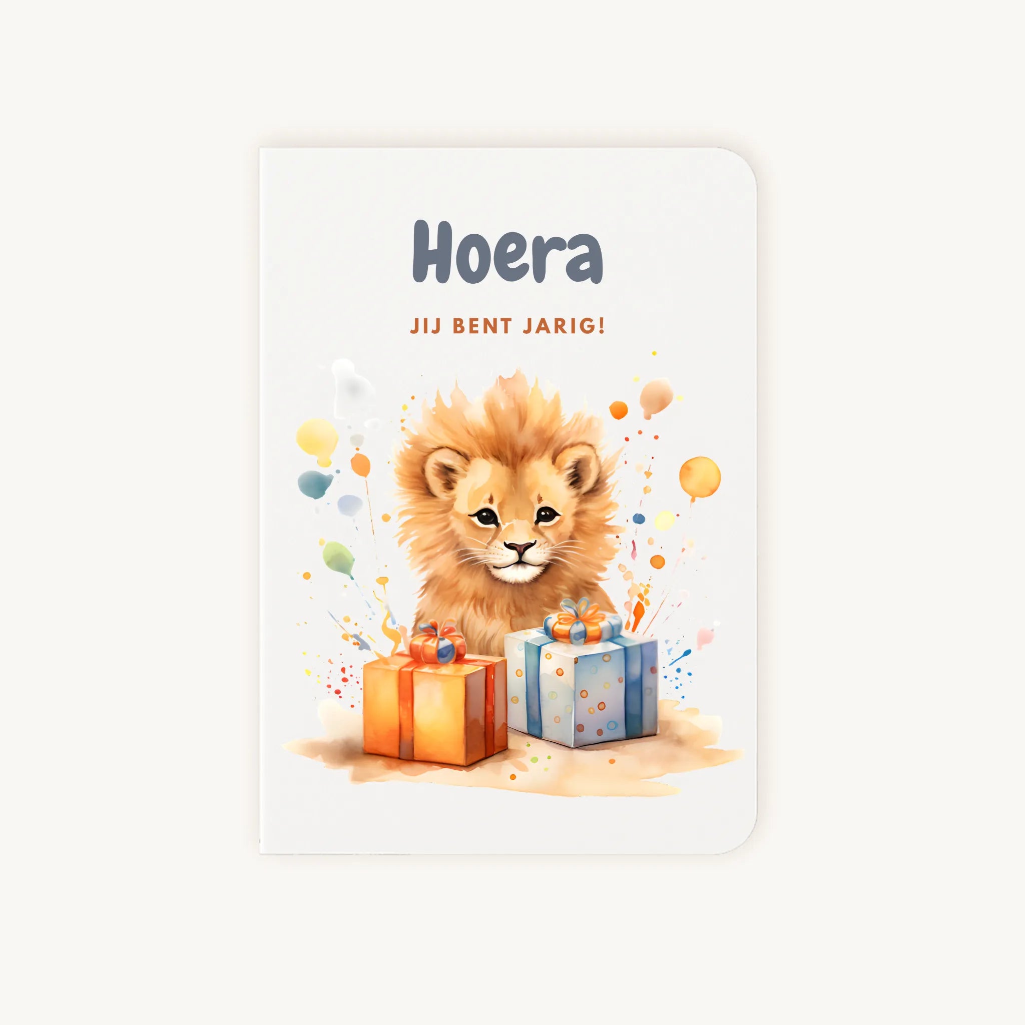 Staande dubbelgevouwen verjaardagskaart met schattige leeuwenwelp tussen kleurrijke cadeautjes en confetti, met tekst Hoera jij bent jarig, flatlay op lichte achtergrond.