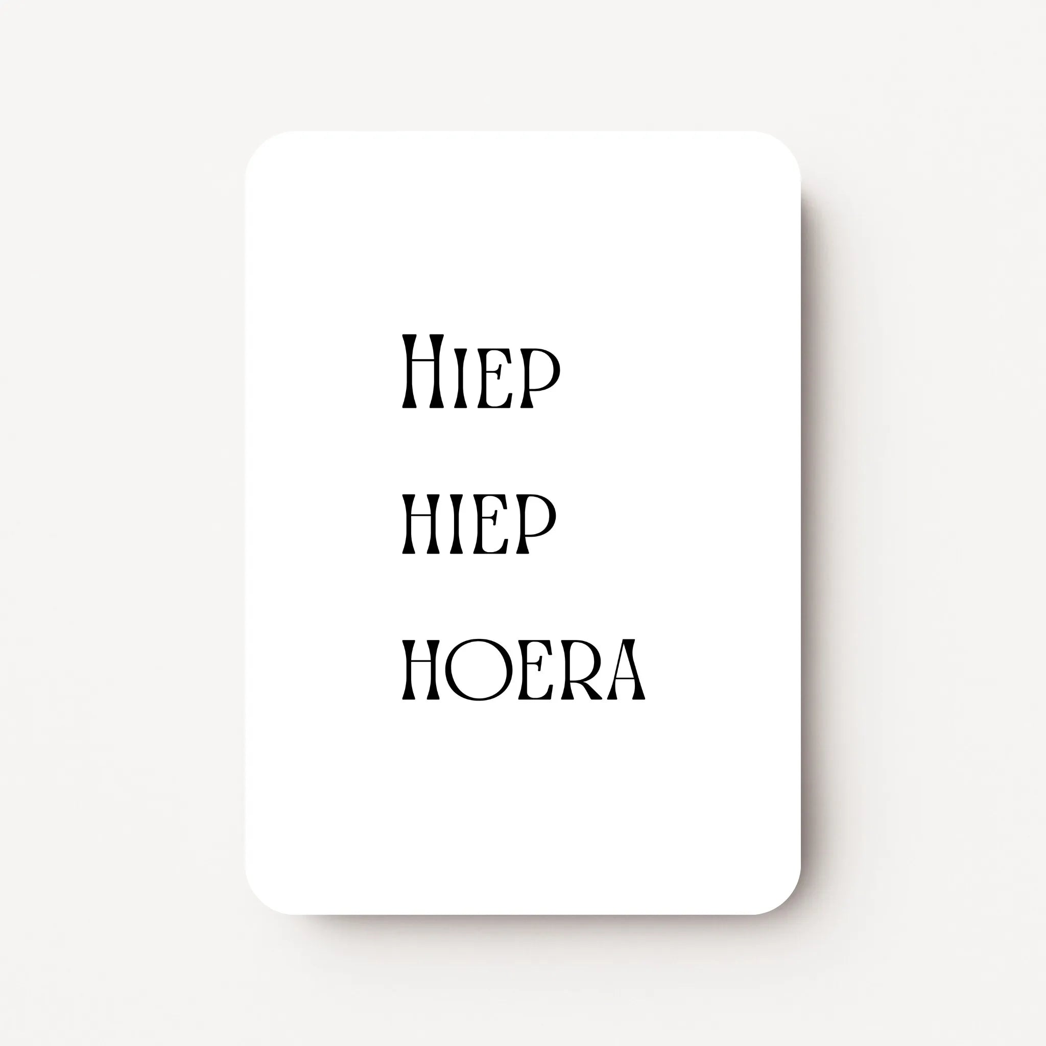 Staande verjaardagskaart voor mannen met zwarte tekst ‘Hiep hiep hoera’, minimalistisch ontwerp op witte achtergrond, flatlay op witte ondergrond.