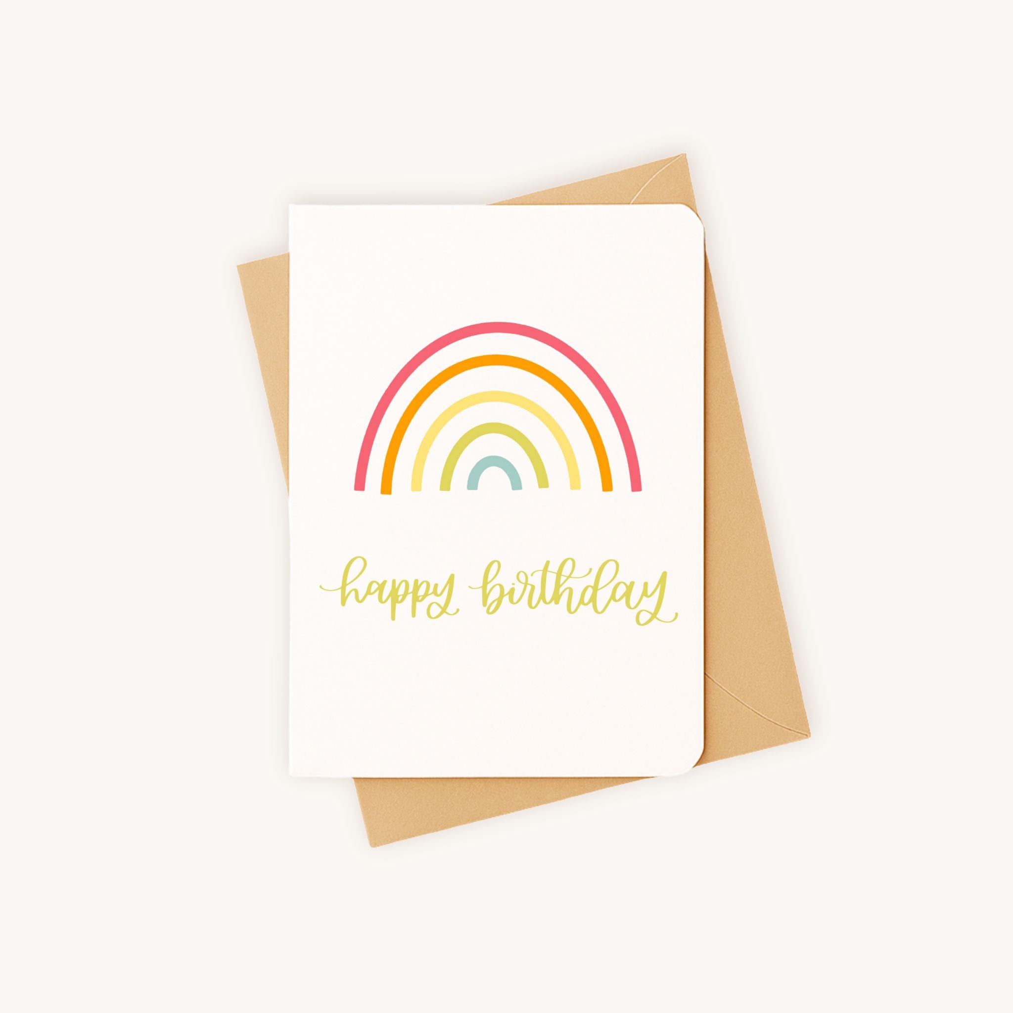 Verjaardagskaart met regenboog liggend naast kraft envelop