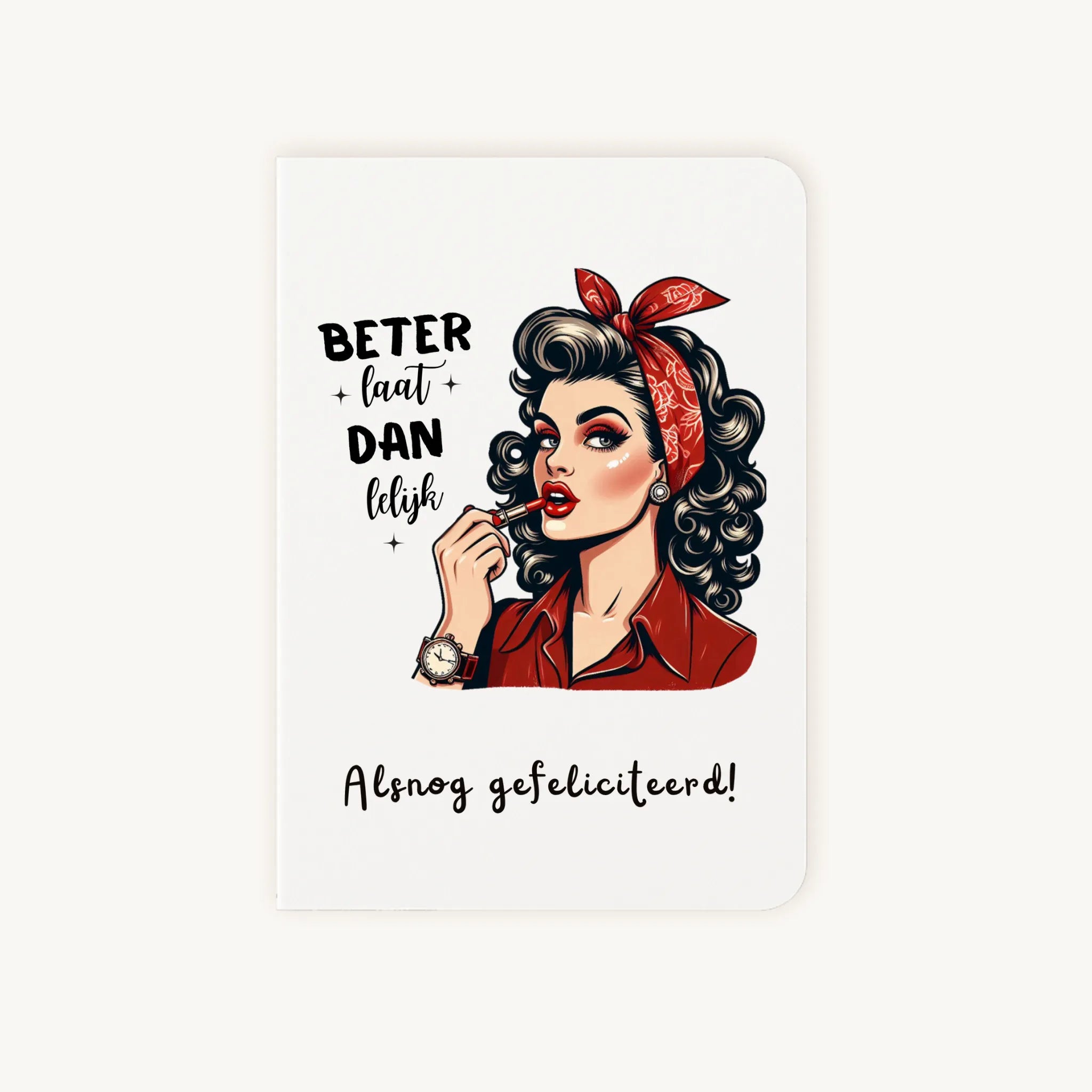 Staande dubbelgevouwen verjaardagskaart met retro illustratie van vrouw met rode lipstick en bandana, met de tekst ‘Beter laat dan lelijk – Alsnog gefeliciteerd’, flatlay op lichte achtergrond.