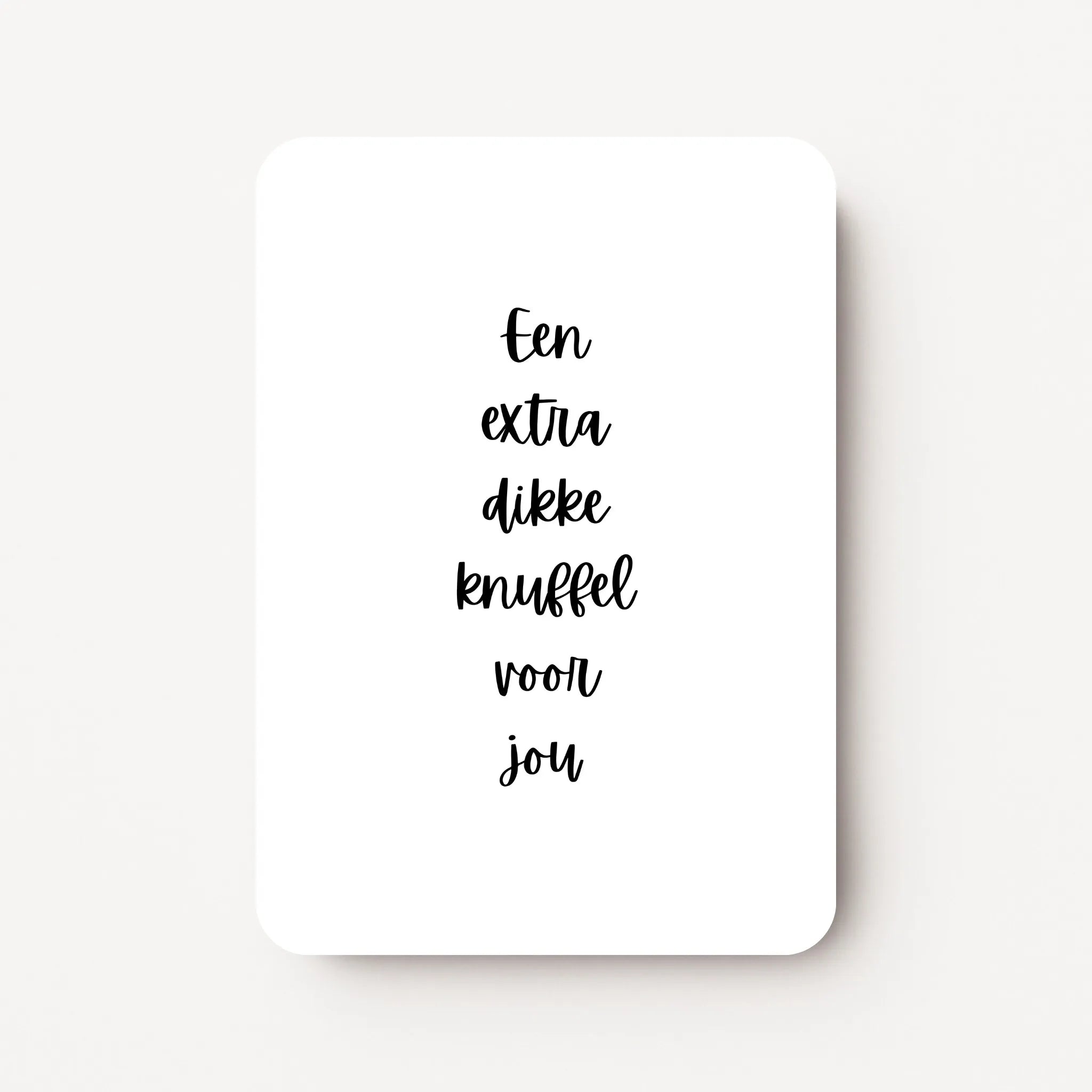 Staande zomaarkaart met zwarte tekst ‘Een extra dikke knuffel voor jou’, flatlay op witte ondergrond.