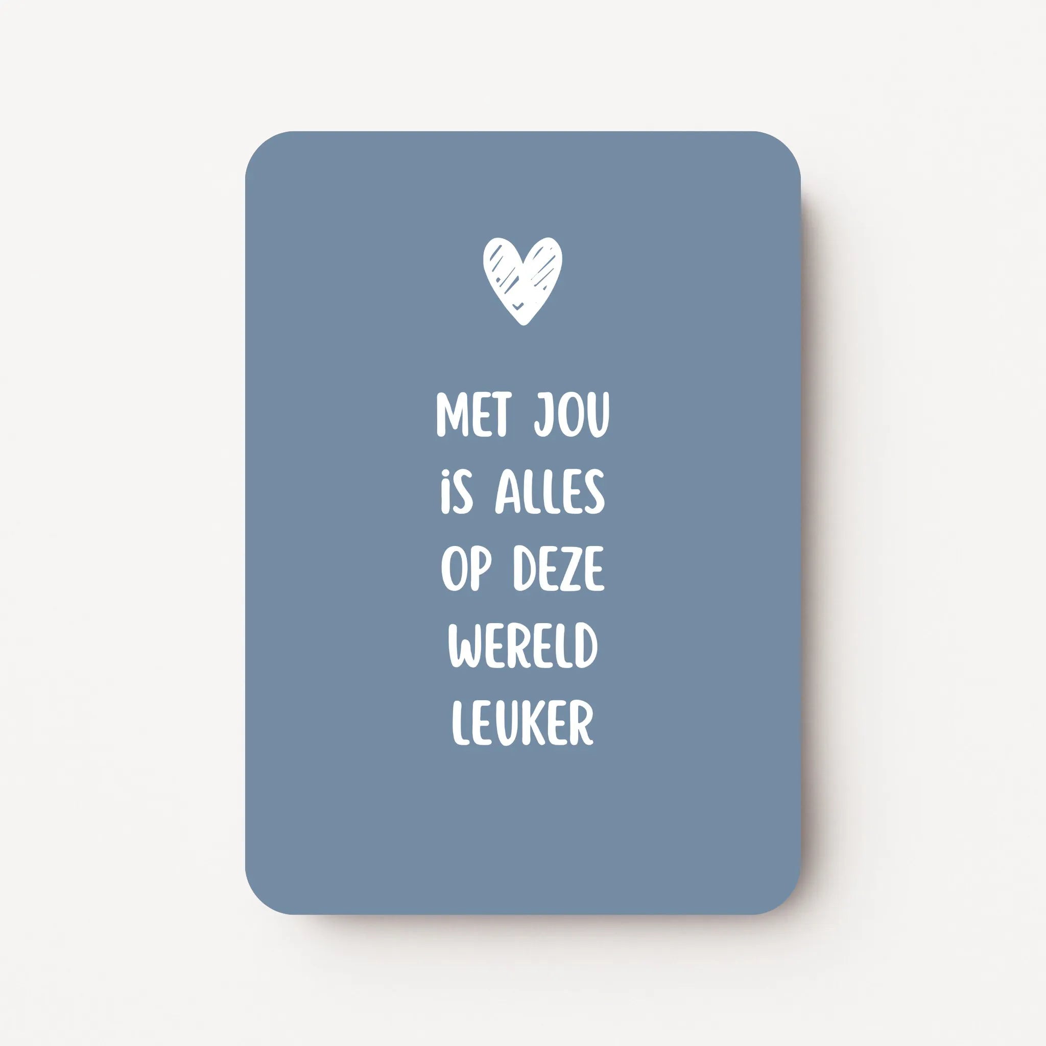 Staande kaart met tekst ‘Met jou is alles op deze wereld leuker’ in witte letters met een wit hartje, op een koele blauwgrijze achtergrond, flatlay op witte ondergrond.