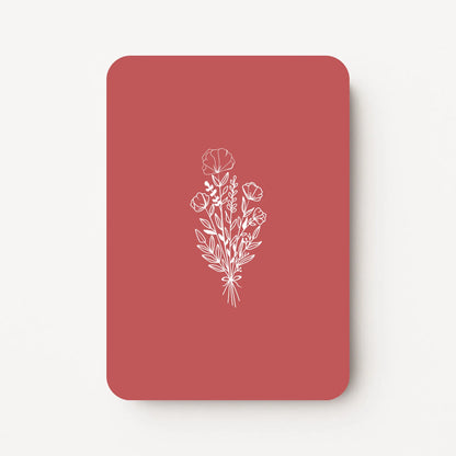 Staande bedankkaart met witte bloemen line art op dieprode achtergrond, flatlay op witte ondergrond.