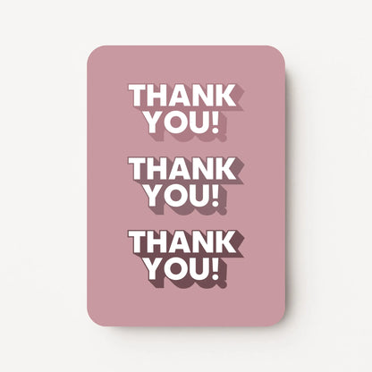 Staande bedankkaart met tekst ‘THANK YOU’ driemaal herhaald, witte letters op oudroze achtergrond, flatlay op witte ondergrond.