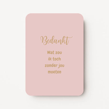 Staande bedankkaart met tekst ‘Bedankt, wat zou ik toch zonder jou moeten’ in sierlijke letters, goudbruine tekst op roze-beige achtergrond, flatlay op witte ondergrond.