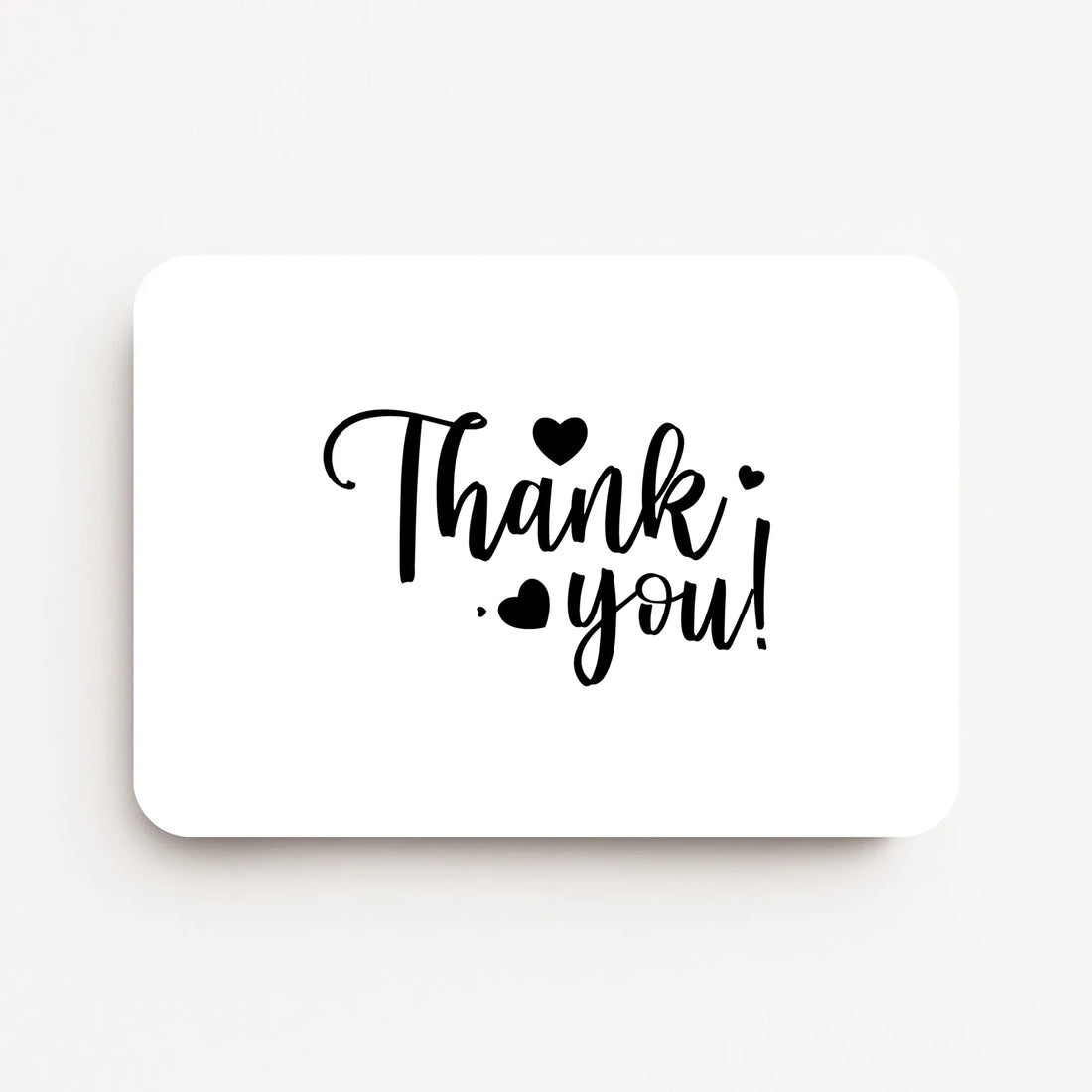 Liggende bedankkaart met tekst ‘Thank you!’ in zwarte letters met kleine hartjes, flatlay op witte achtergrond.
