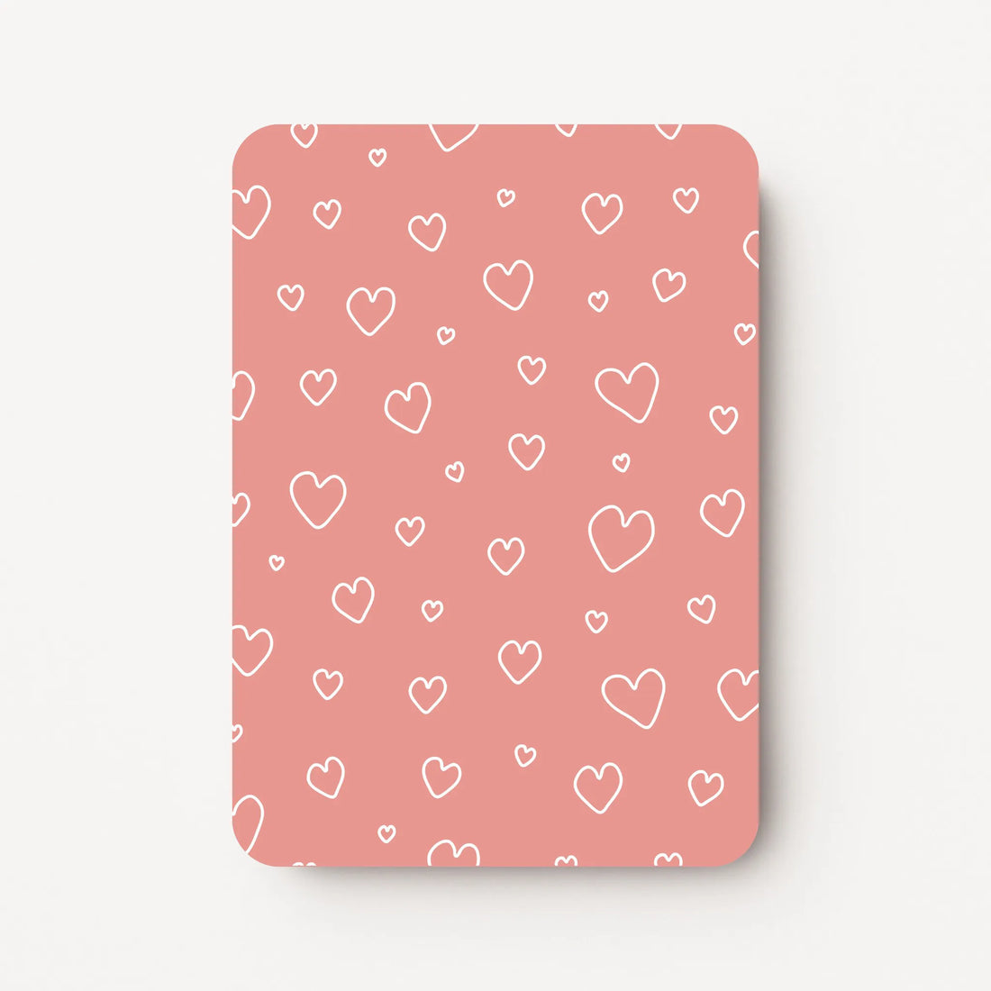 Staande beterschapskaart met witte hartjes in verschillende maten op een warme zalmroze achtergrond, flatlay op witte ondergrond.