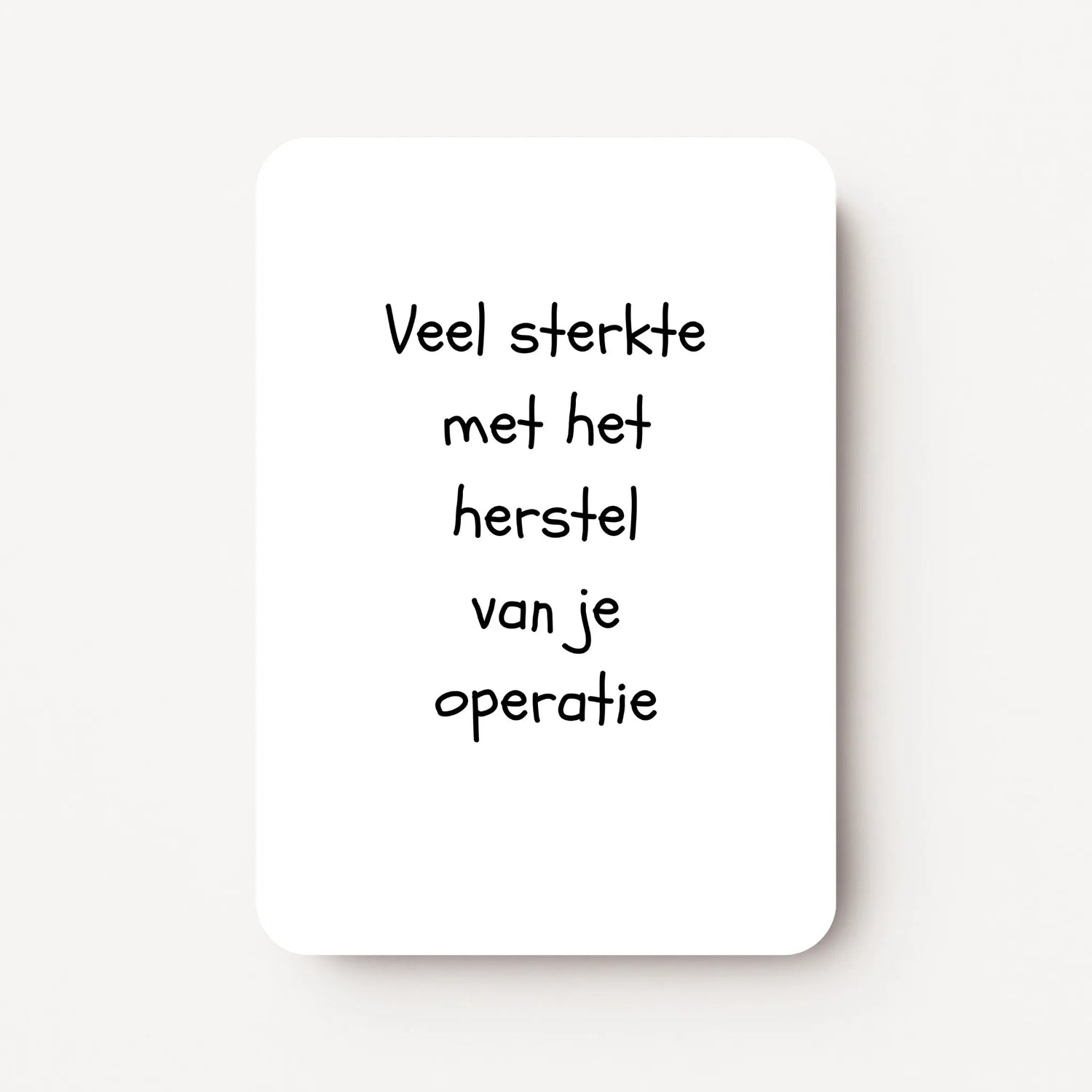 Staande beterschapskaart met zwarte tekst ‘Veel sterkte met het herstel van je operatie’ op witte achtergrond, minimalistisch ontwerp, flatlay op witte ondergrond.
