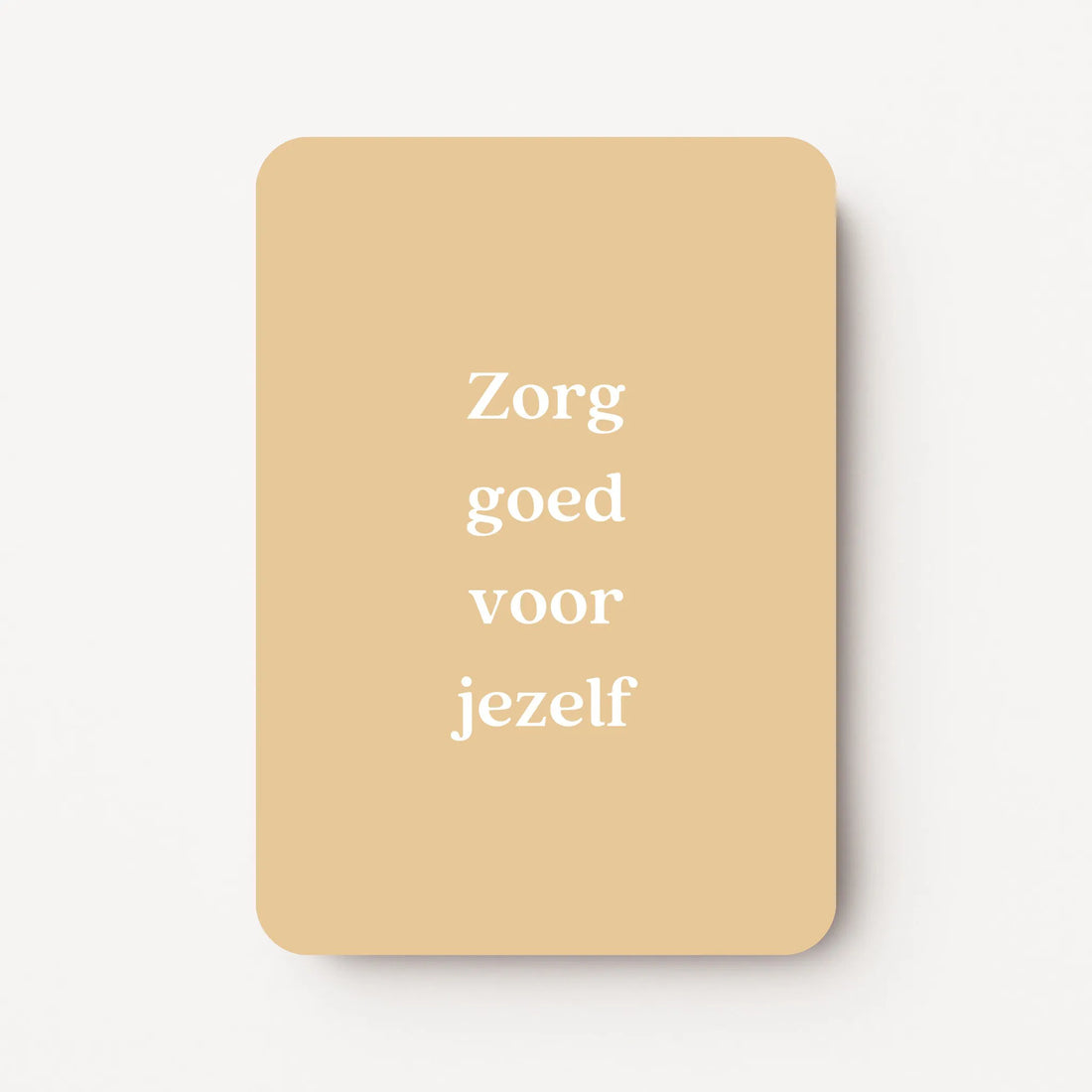 Staande beterschapskaart met witte tekst ‘Zorg goed voor jezelf’ op een zachte honinggele achtergrond, flatlay op witte ondergrond.