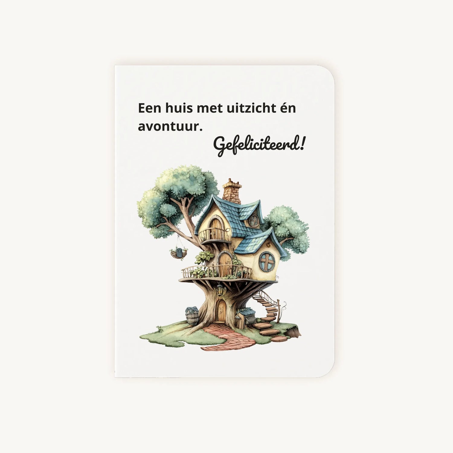 Staande dubbelgevouwen kaart nieuwe woning met afgeronde hoekjes en kleurrijke aquarelillustratie van een boomhuis, met de tekst Een huis met uitzicht en avontuur Gefeliciteerd, flatlay op lichte achtergrond.