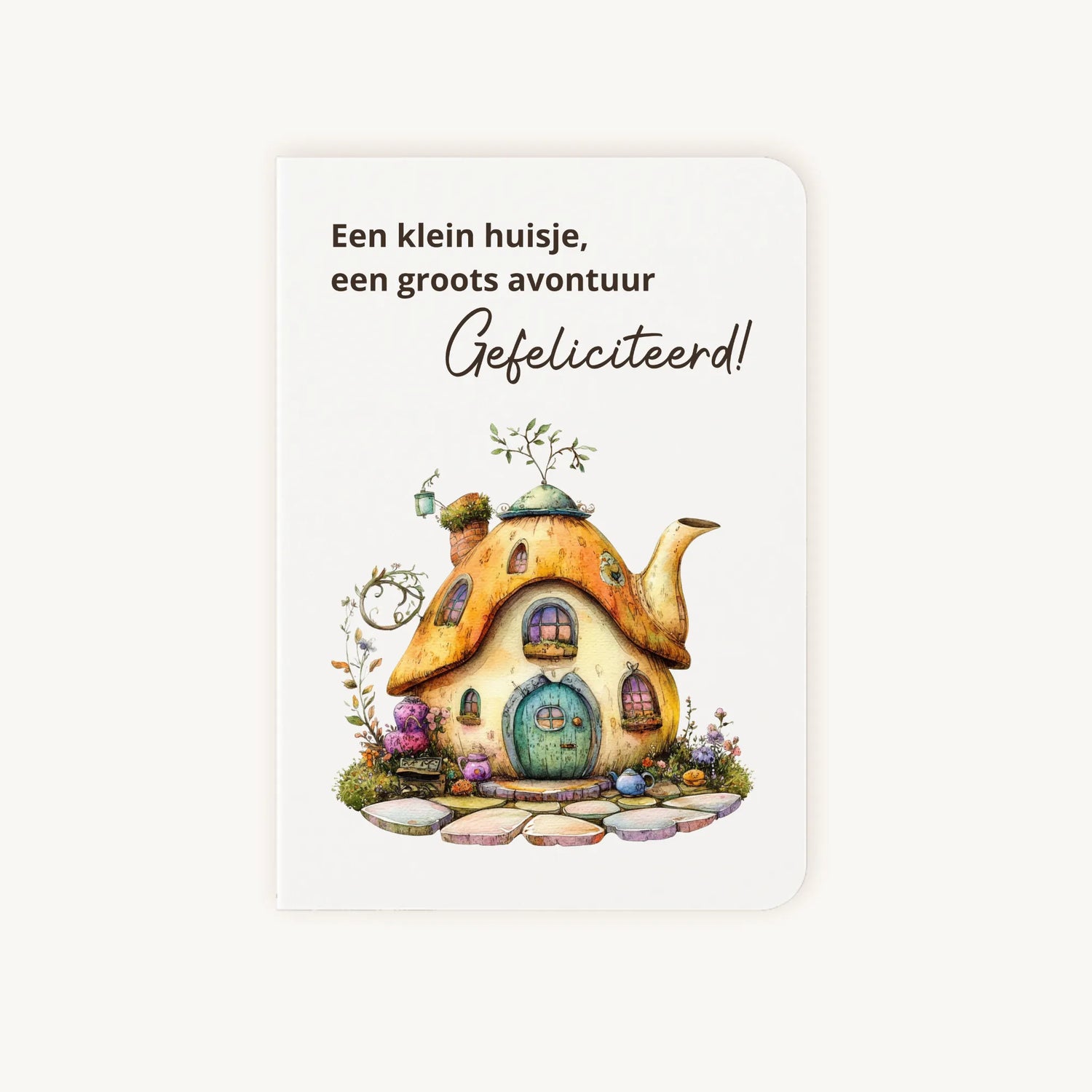 Staande dubbelgevouwen kaart nieuwe woning met afgeronde hoekjes en aquarelillustratie van een sprookjesachtig theepot huisje, met de tekst Een klein huisje een groots avontuur Gefeliciteerd, flatlay op lichte achtergrond.