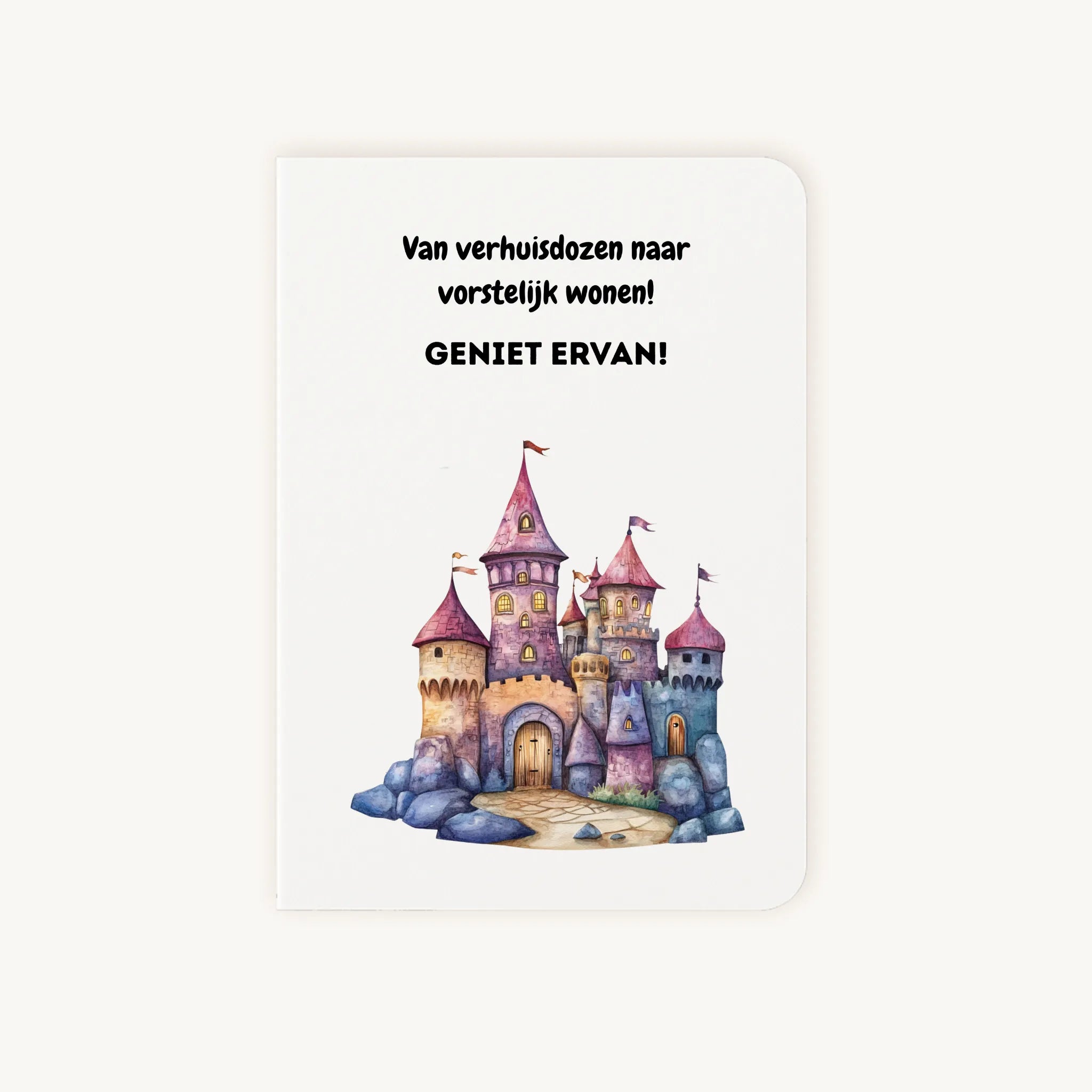 Staande dubbelgevouwen felicitatiekaart nieuwe woning met afgeronde hoekjes en kleurrijke aquarelillustratie van een sprookjeskasteel, met de tekst Van verhuisdozen naar vorstelijk wonen Geniet ervan, flatlay op lichte achtergrond.