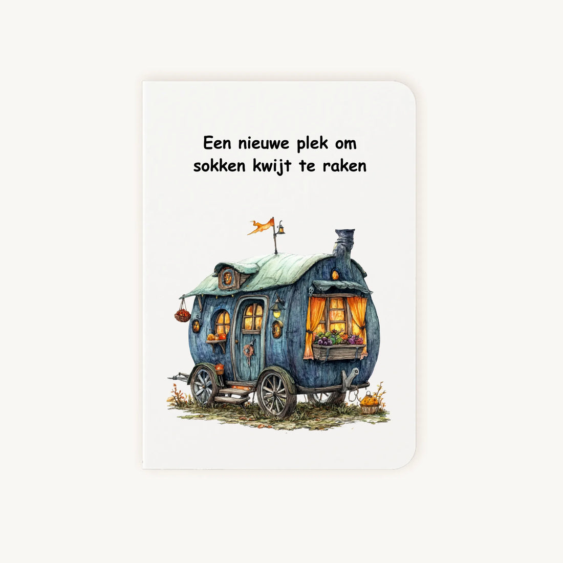 Staande dubbelgevouwen kaart nieuwe woning met afgeronde hoekjes en aquarelillustratie van een blauwgroene woonwagen, met de tekst Een nieuwe plek om sokken kwijt te raken, flatlay op lichte achtergrond.