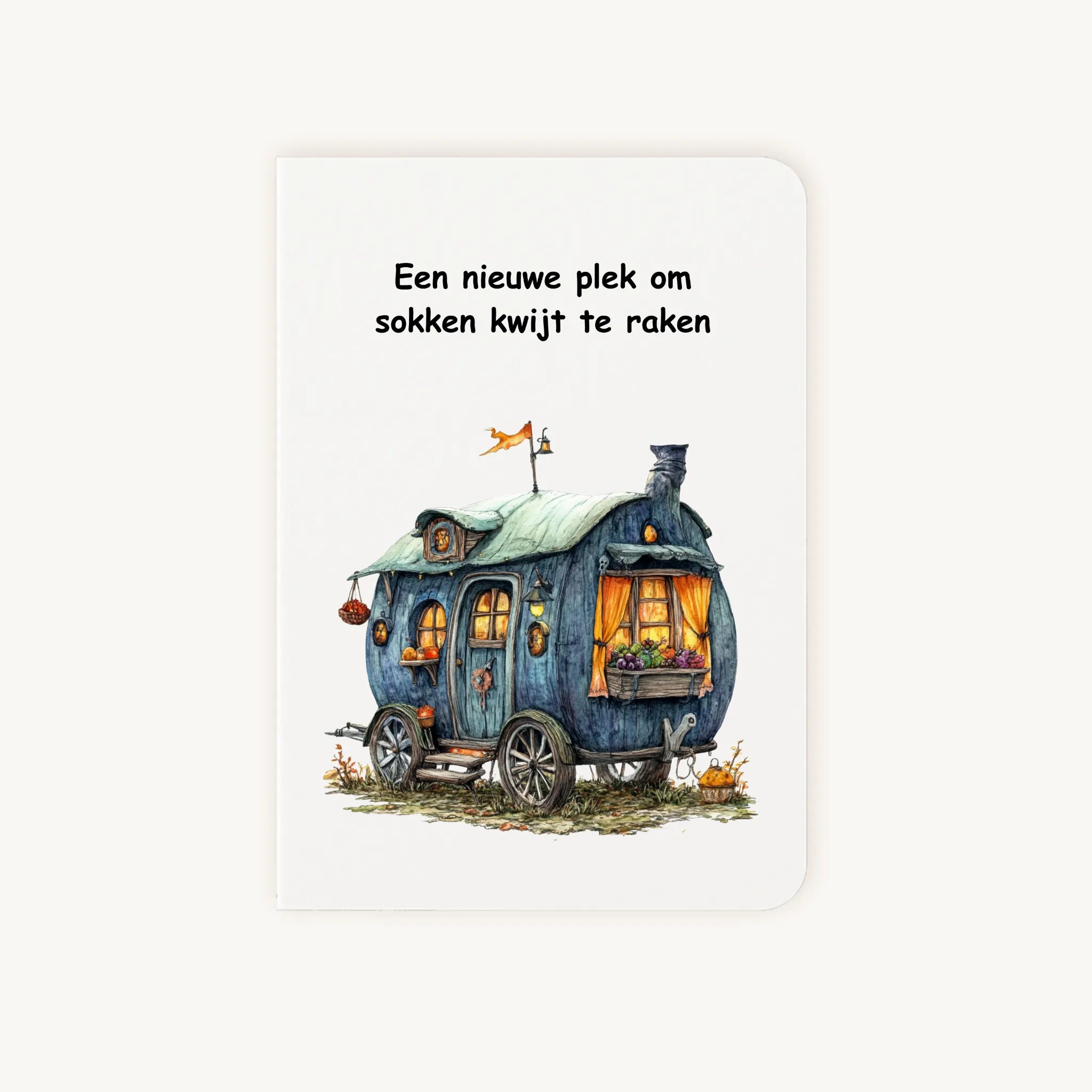 Staande dubbelgevouwen kaart nieuwe woning met afgeronde hoekjes en aquarelillustratie van een blauwgroene woonwagen, met de tekst Een nieuwe plek om sokken kwijt te raken, flatlay op lichte achtergrond.