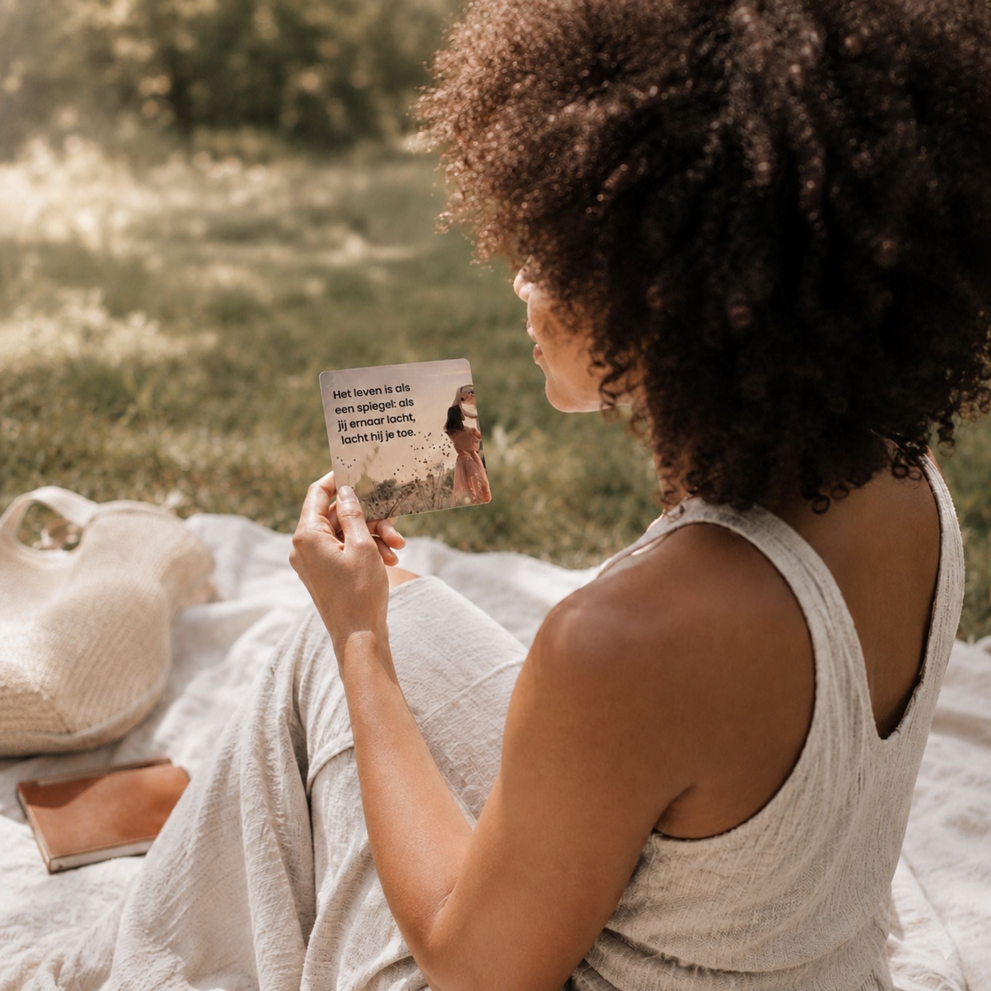 Vrouw leest buiten een dagelijkse affirmatiekaart uit de 365 dagen collectie tijdens een rustig moment in de natuur.
