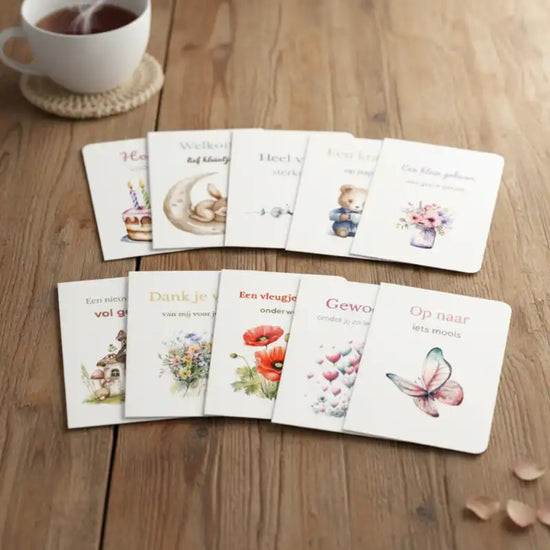 Set van 10 wenskaarten op een houten tafel, met een kop thee erbij – overzicht van de kaartenset in een warme, uitnodigende en gezellige sfeer.