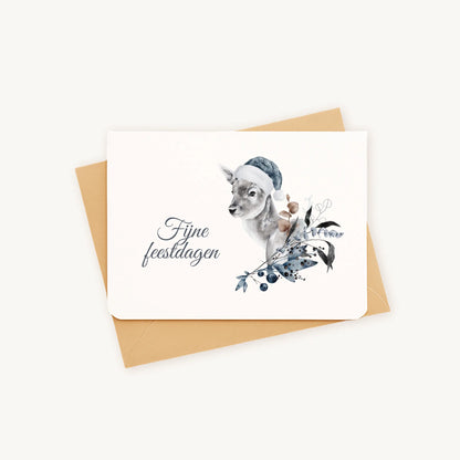 Liggende kerstkaart met aquarel hert met blauwe kerstmuts en winterse bladeren en bessen, sierlijke tekst ‘fijne feestdagen’, op kraftenvelop op lichte achtergrond.