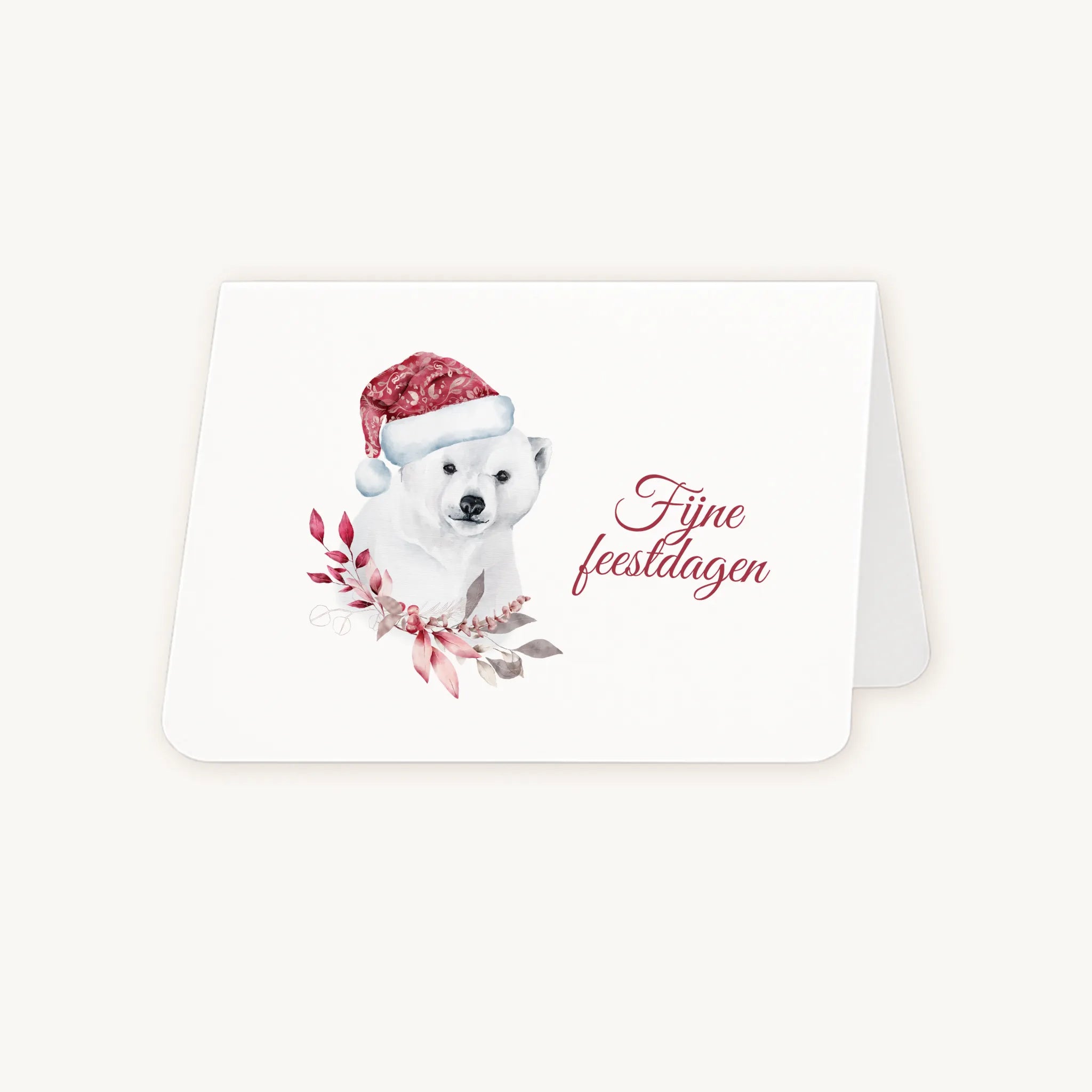 Half geopende liggende kerstkaart met aquarel ijsbeer met rode kerstmuts en winterse bladeren, sierlijke tekst ‘fijne feestdagen’, op lichte achtergrond.