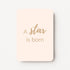 Staande minikaart met goudbeige tekst "A star is born", minimalistisch ontwerp op een zachte perzik-witte achtergrond.