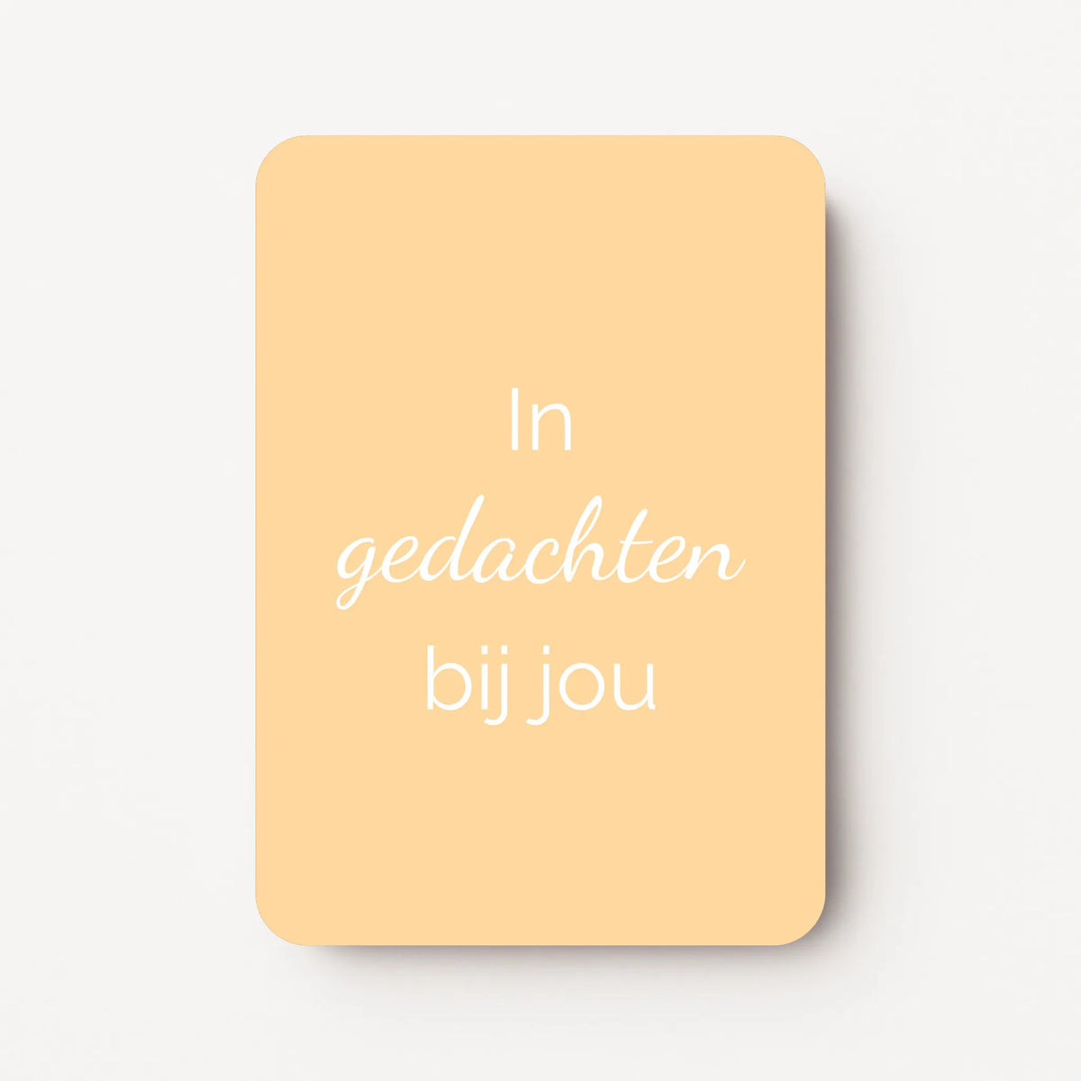 Staande minikaart met witte tekst "In gedachten bij jou", minimalistisch ontwerp op een warme lichtgele achtergrond.