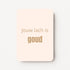 Staande minikaart met goudbeige tekst "Jouw lach is GOUD", minimalistisch ontwerp op een zachte perzik-witte achtergrond.