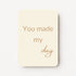 Staande minikaart met goudbeige tekst "You made my day", minimalistisch ontwerp op een zachte crèmekleurige achtergrond.
