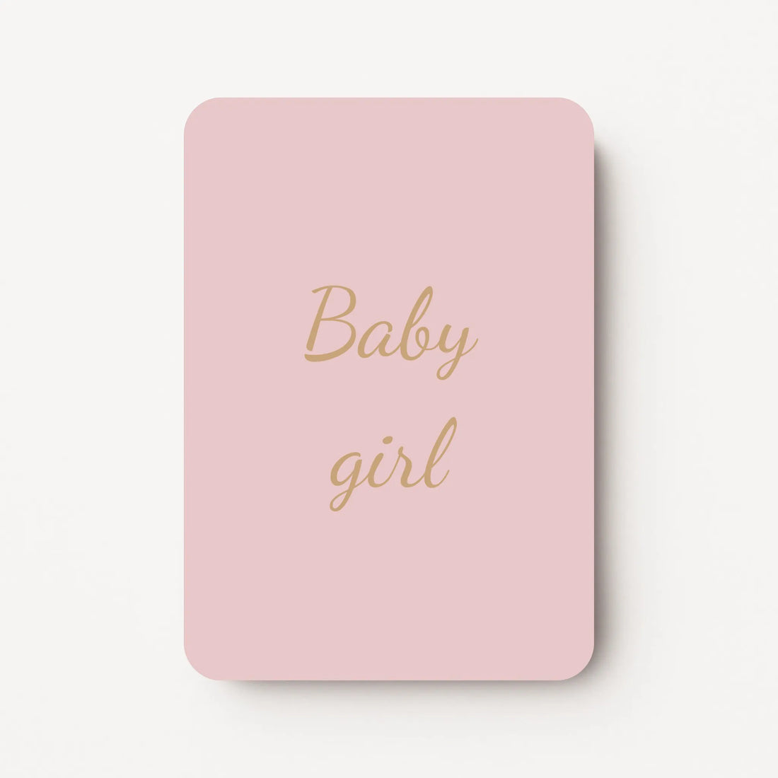 Staand minikaartje met tekst ‘Baby girl’ in goudbeige letters, minimalistisch ontwerp op zachte warmgrijze achtergrond met een vleugje roze, flatlay op witte ondergrond.