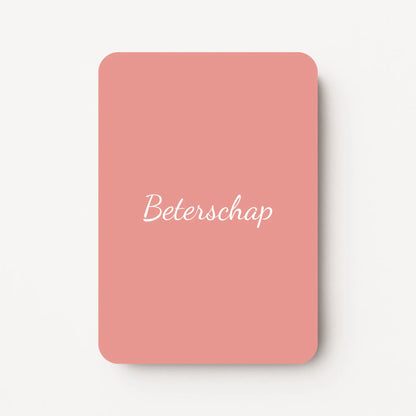 Staand minikaartje met tekst ‘Beterschap’ in witte letters, minimalistisch ontwerp op zachte oudroze achtergrond, flatlay op witte ondergrond.