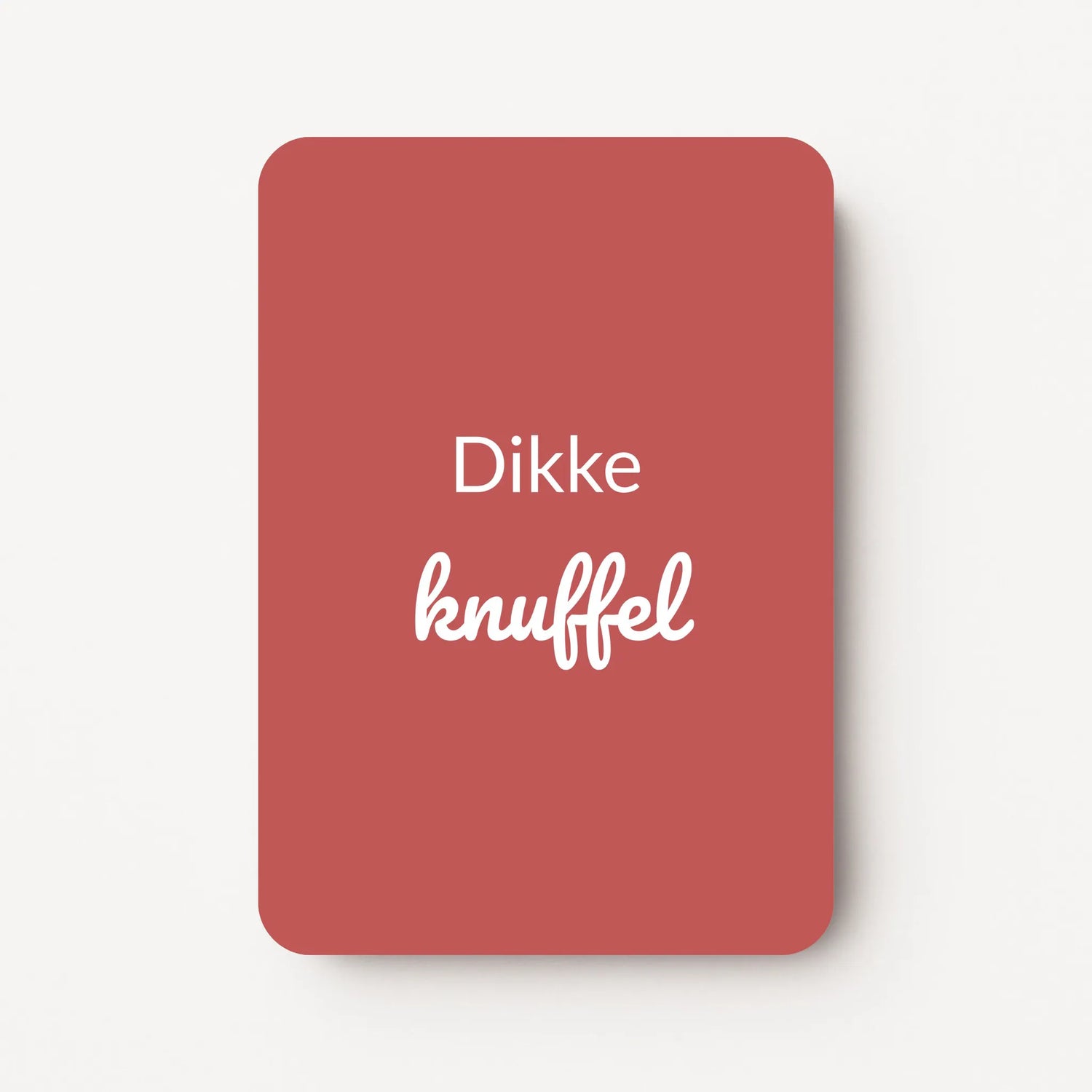 Staand minikaartje met witte tekst ‘Dikke knuffel’, minimalistisch ontwerp op een diepe bordeauxrode achtergrond, flatlay op witte ondergrond.