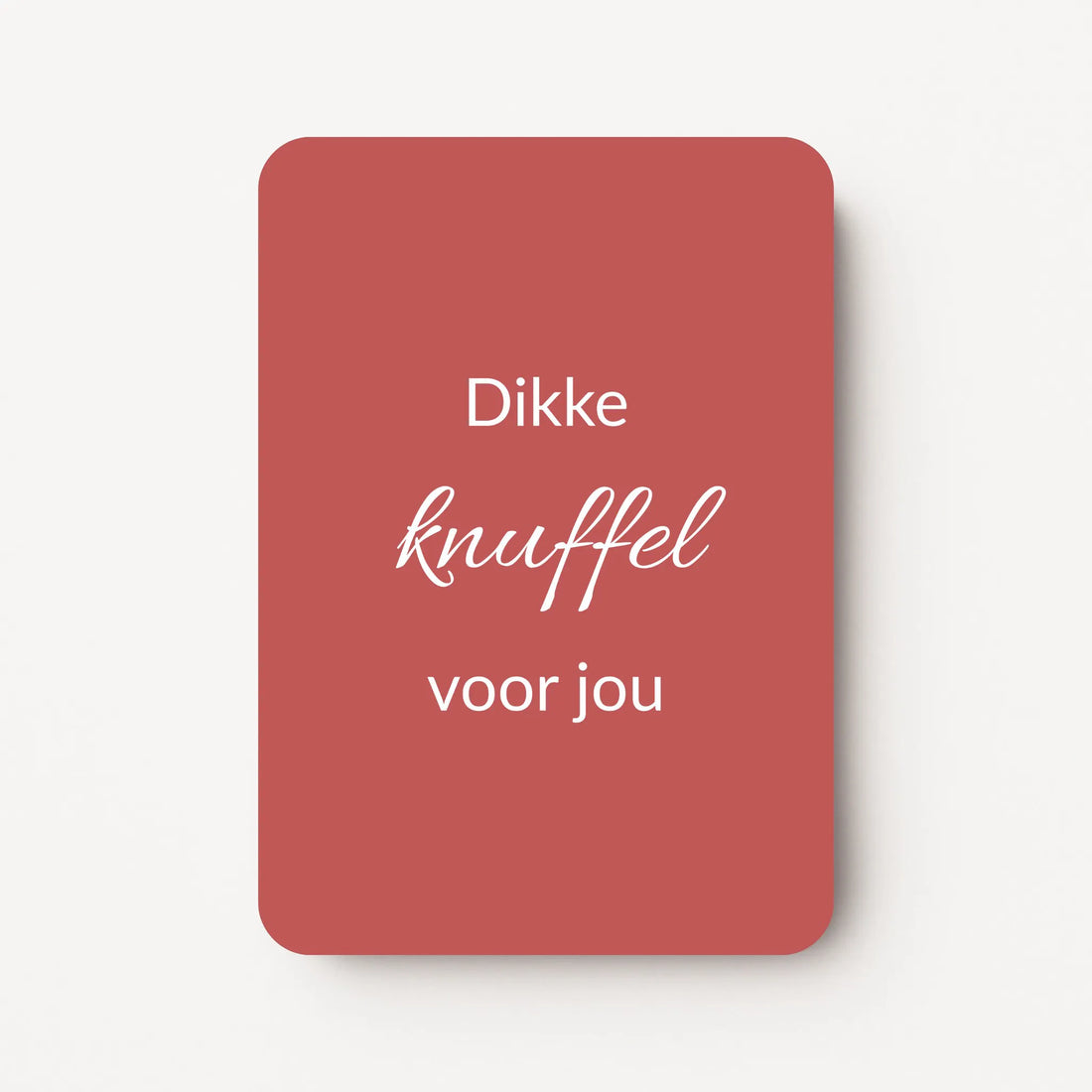 Staand minikaartje met tekst ‘Dikke knuffel voor jou’ in witte letters, minimalistisch ontwerp op warme bordeauxrode achtergrond, flatlay op witte ondergrond.