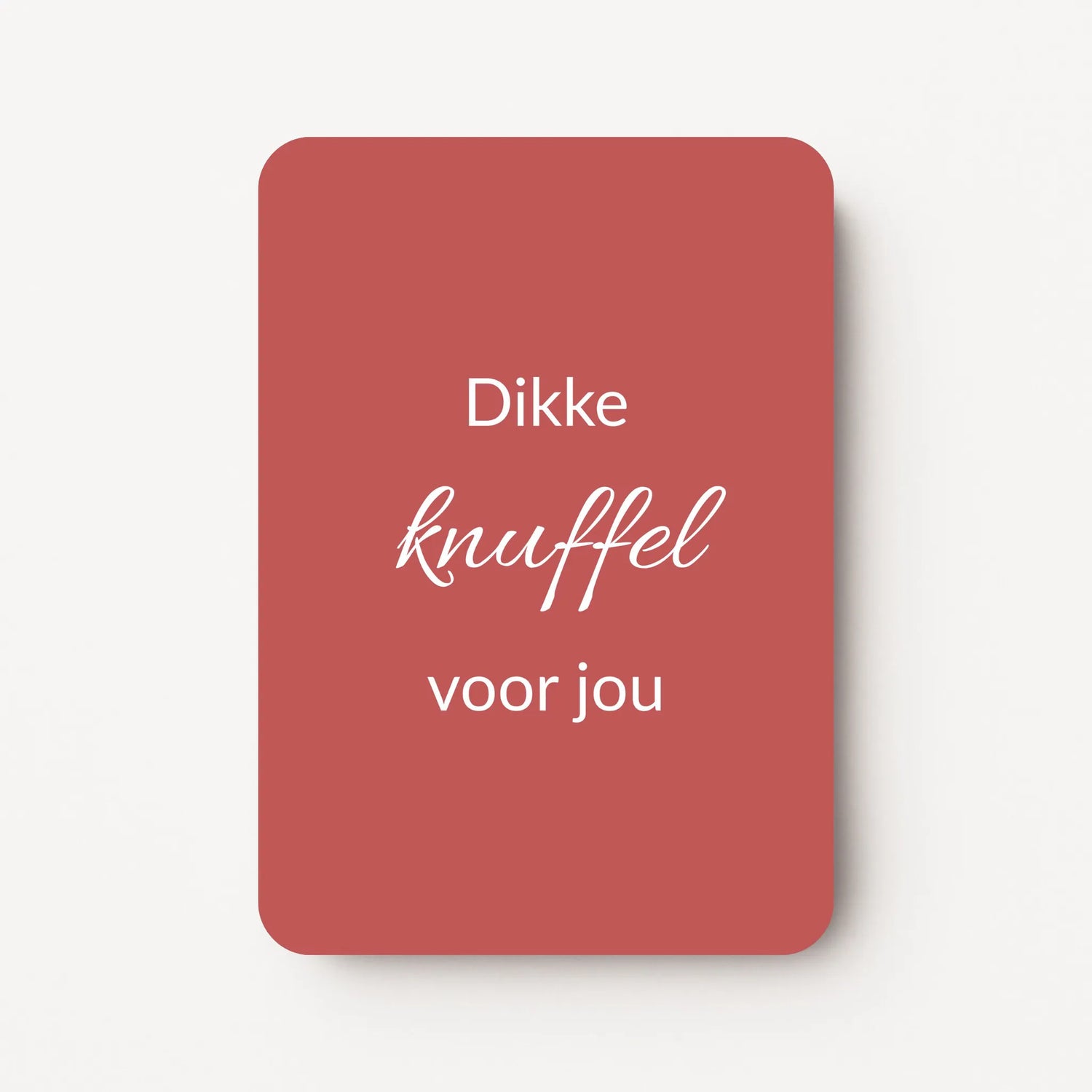 Staand minikaartje met tekst ‘Dikke knuffel voor jou’ in witte letters, minimalistisch ontwerp op warme bordeauxrode achtergrond, flatlay op witte ondergrond.
