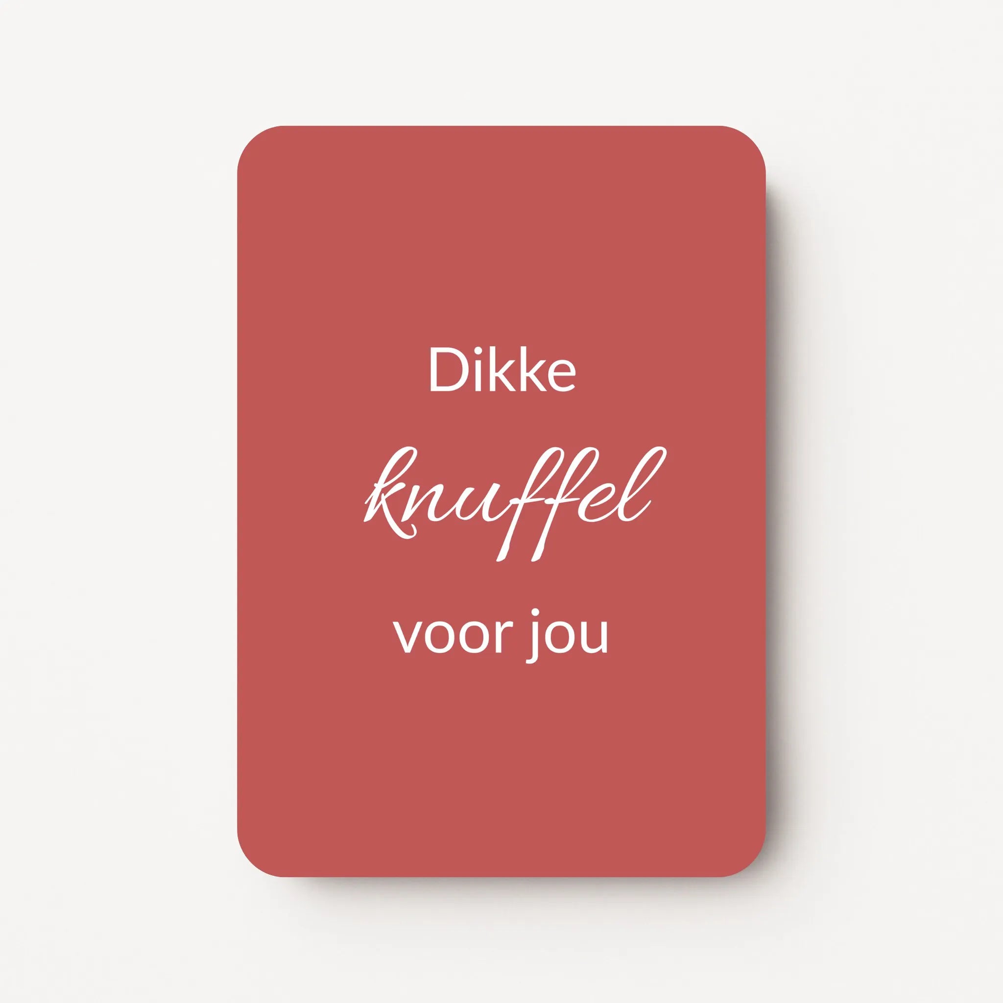 Staand minikaartje met tekst ‘Dikke knuffel voor jou’ in witte letters, minimalistisch ontwerp op warme bordeauxrode achtergrond, flatlay op witte ondergrond.