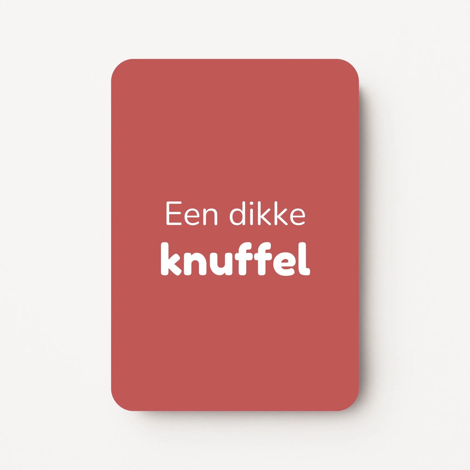 Staand minikaartje met witte tekst ‘Een dikke knuffel’, minimalistisch ontwerp op een warme dieproze achtergrond, flatlay op witte ondergrond.