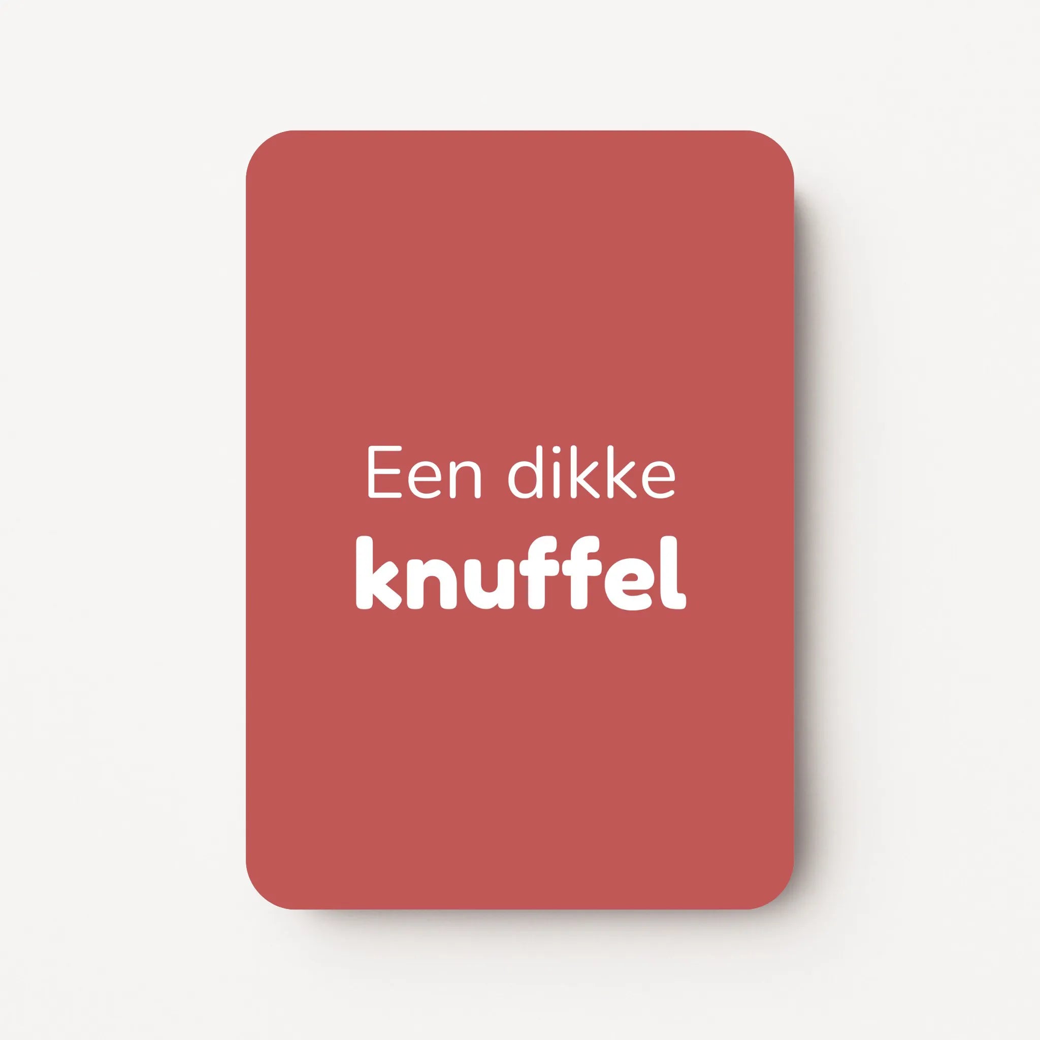 Staand minikaartje met witte tekst ‘Een dikke knuffel’, minimalistisch ontwerp op een warme dieproze achtergrond, flatlay op witte ondergrond.