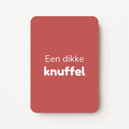 Staand minikaartje met witte tekst ‘Een dikke knuffel’, minimalistisch ontwerp op een warme dieproze achtergrond, flatlay op witte ondergrond.