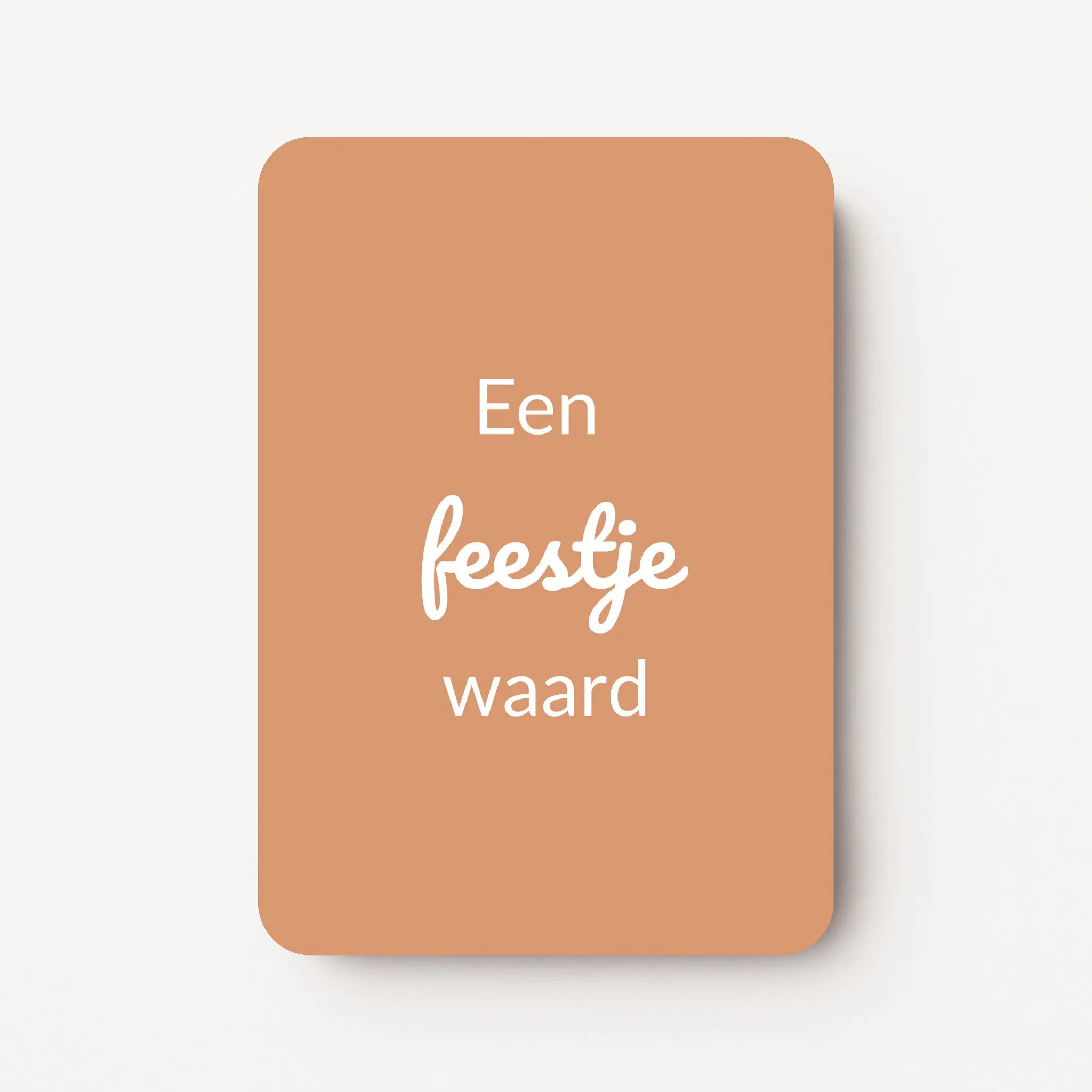 Staand minikaartje met witte tekst ‘Een feestje waard’, minimalistisch ontwerp op warme caramelkleurige achtergrond, flatlay op witte ondergrond.