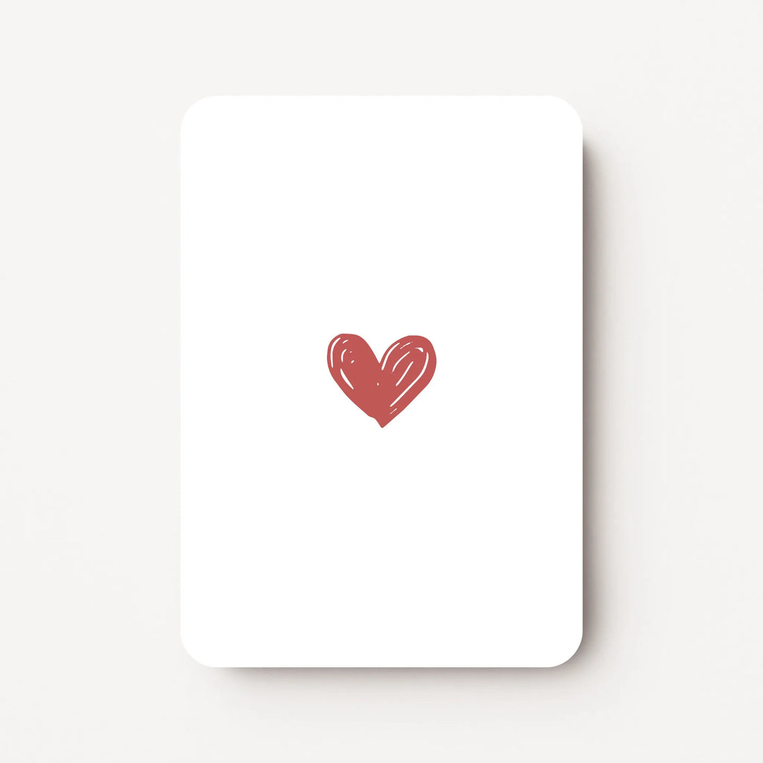 Staand minikaartje met een enkel hartje in warm roodroze kleur, minimalistisch ontwerp op witte achtergrond, flatlay op witte ondergrond.