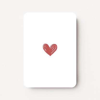 Staand minikaartje met een enkel hartje in warm roodroze kleur, minimalistisch ontwerp op witte achtergrond, flatlay op witte ondergrond.