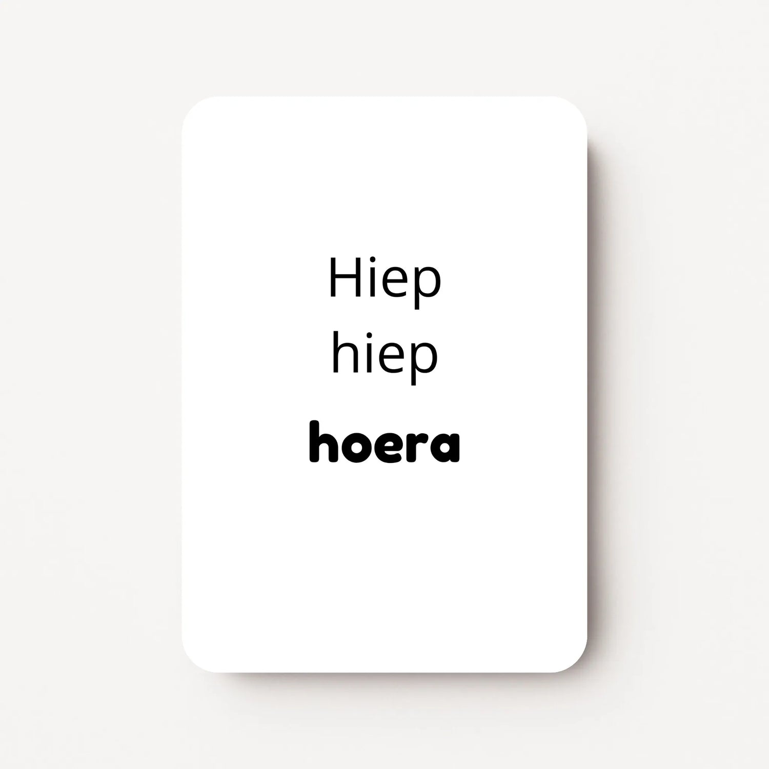 Staand minikaartje met zwarte tekst ‘Hiep hiep hoera’, minimalistisch ontwerp op witte achtergrond, flatlay op witte ondergrond.