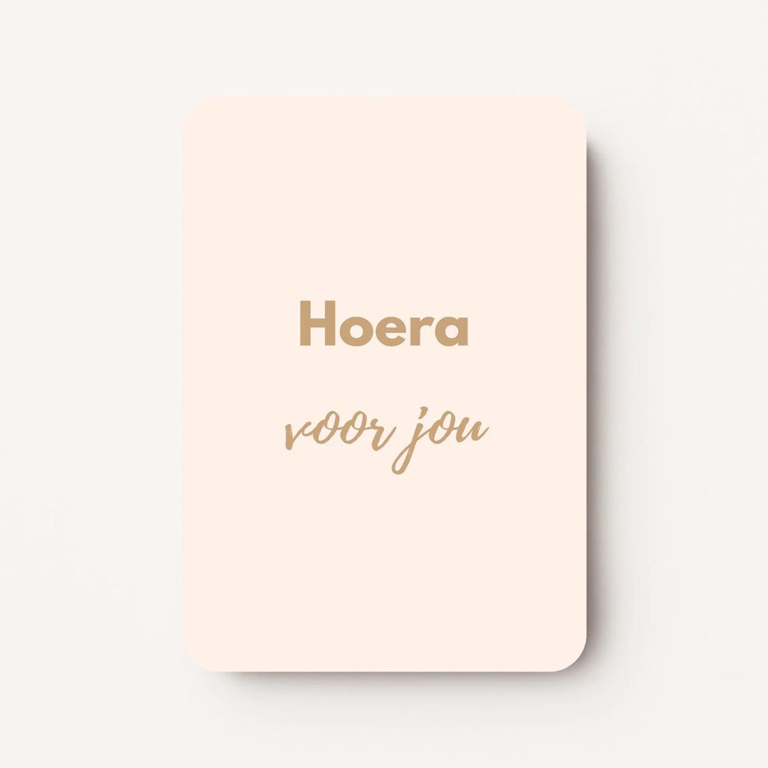 Staand minikaartje met goudbeige tekst ‘Hoera voor jou’, minimalistisch ontwerp op zachte roomkleurige achtergrond, flatlay op witte ondergrond.
